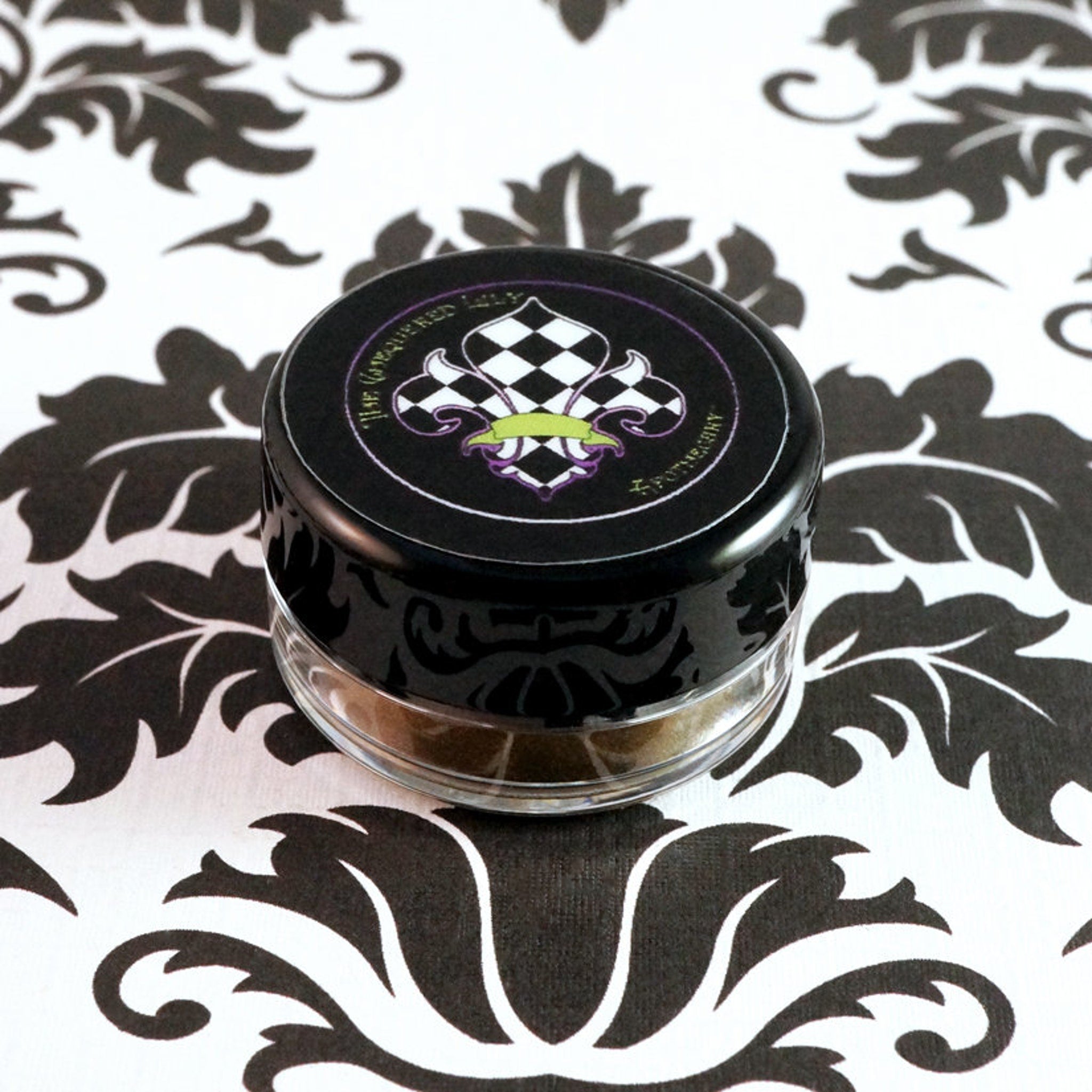 Swatch of metallic bronze loose eyeshadow with dark gold base and green glitter sparkles on fingertip