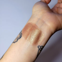 Close-up of shimmering quartz eye shadow with iridescent pink and gold flecks in compact palette