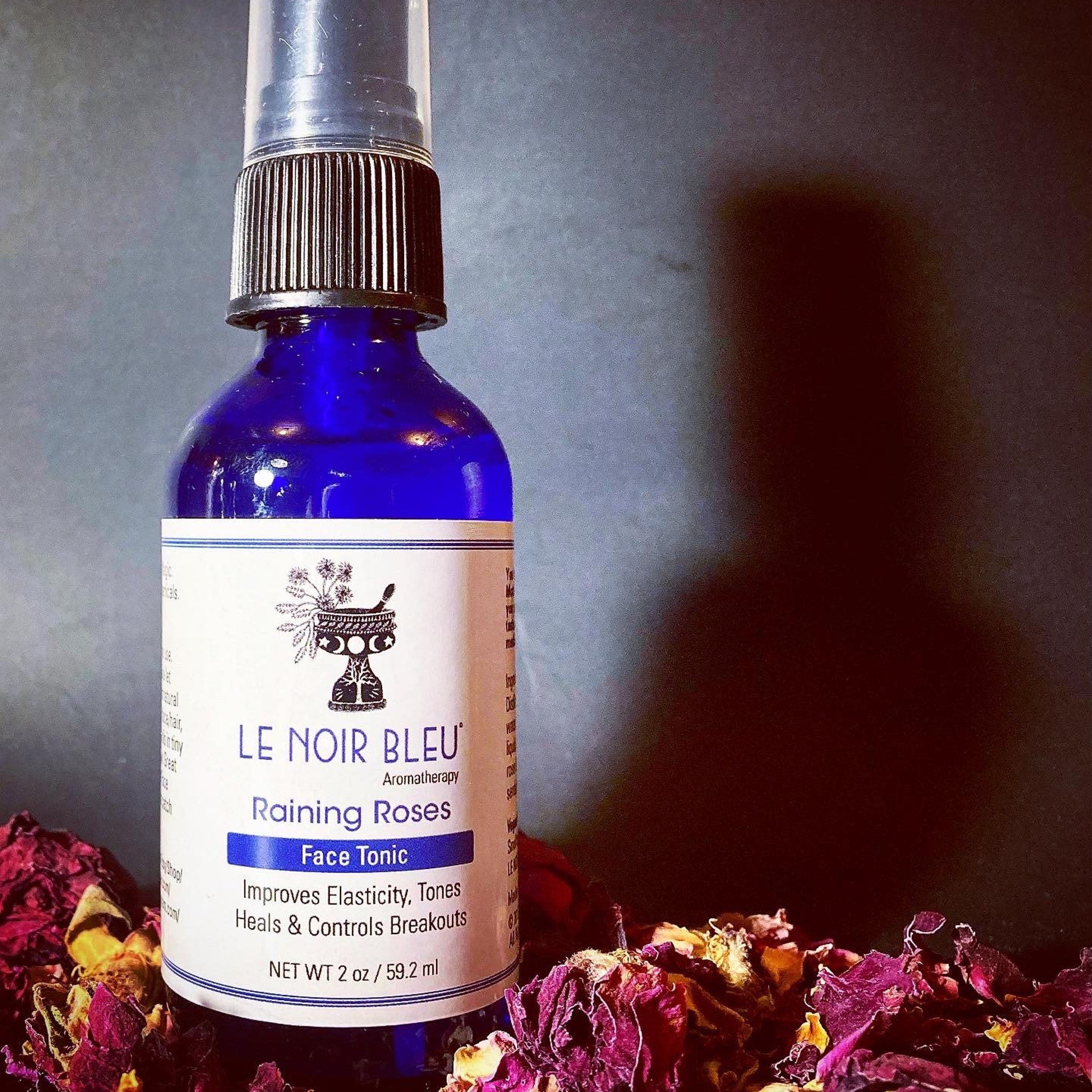 Face tonic bottle with blue glass, black spray top, and white label with text