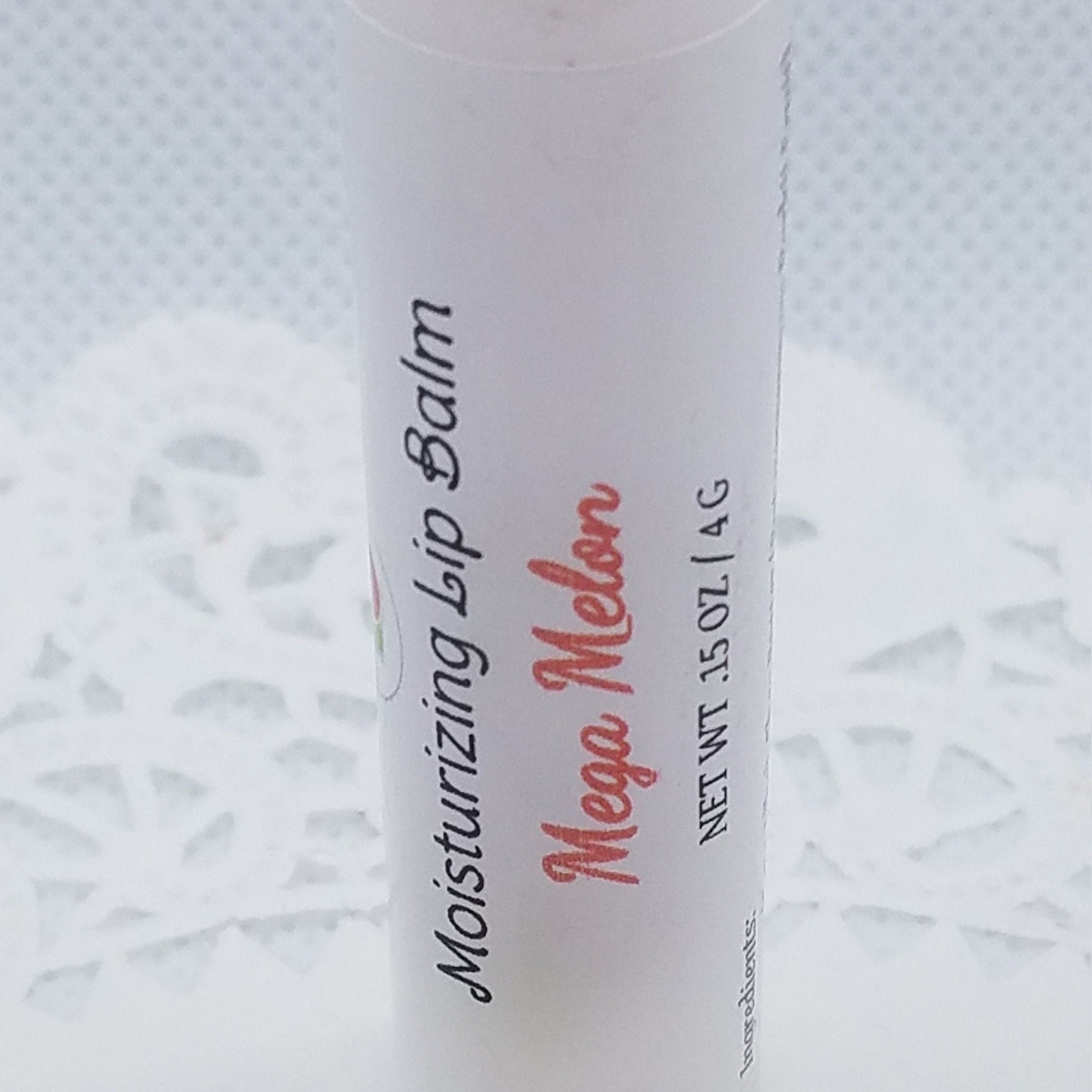 Lip balm tube with white label, black and red text, and patterned background