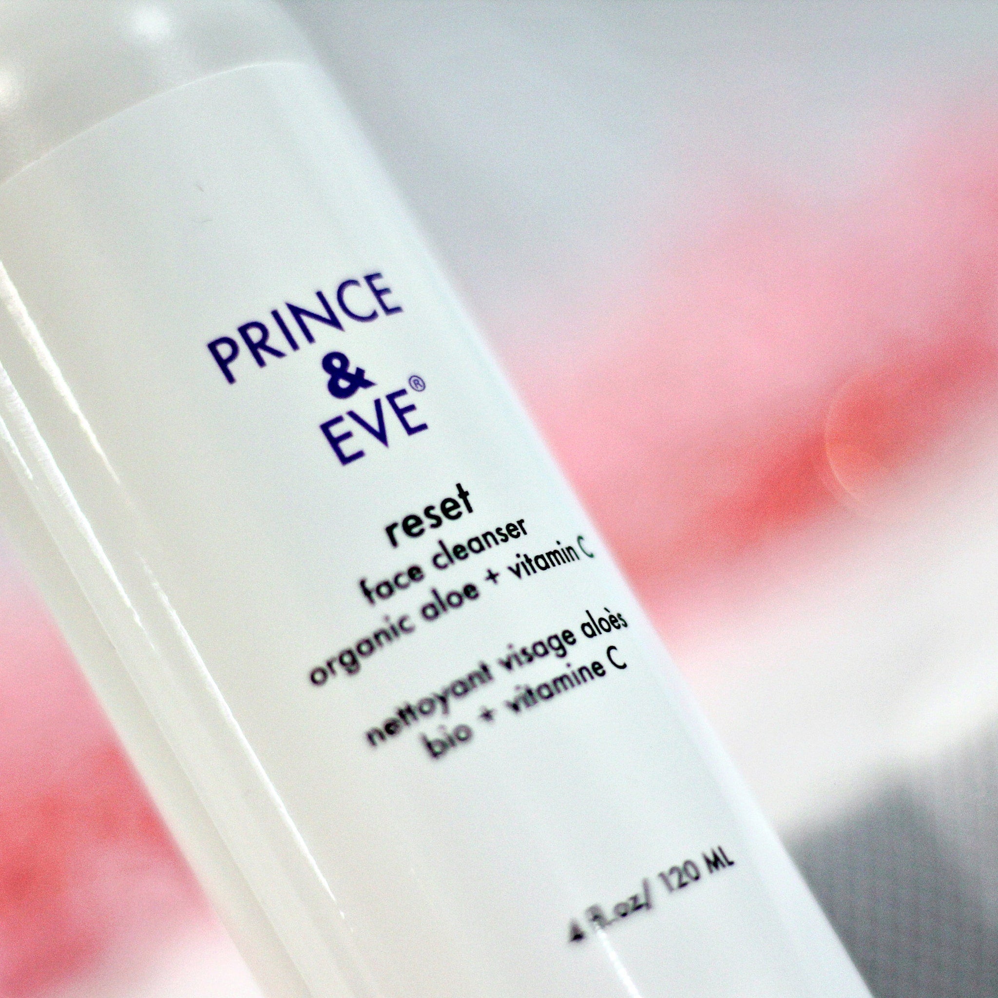 Face cleanser bottle, white plastic, purple text, "PRINCE & EVE" brand visible, pink background