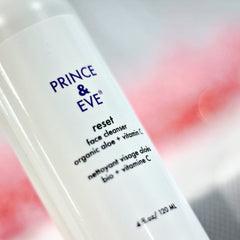 Face cleanser bottle, white plastic, purple text, "PRINCE & EVE" brand visible, pink background