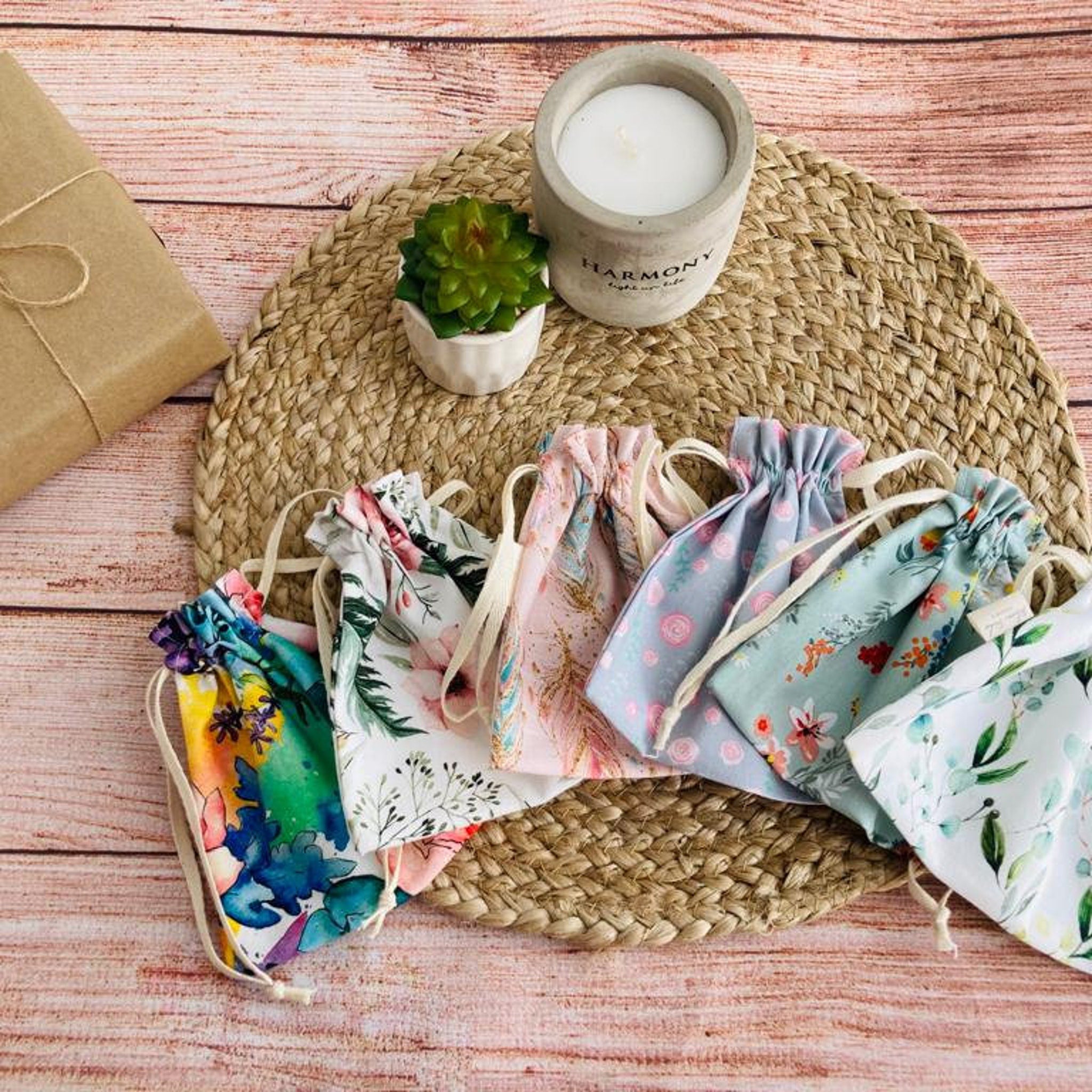 Drawstring bags with floral patterns, various colors, and drawstring closure on woven mat