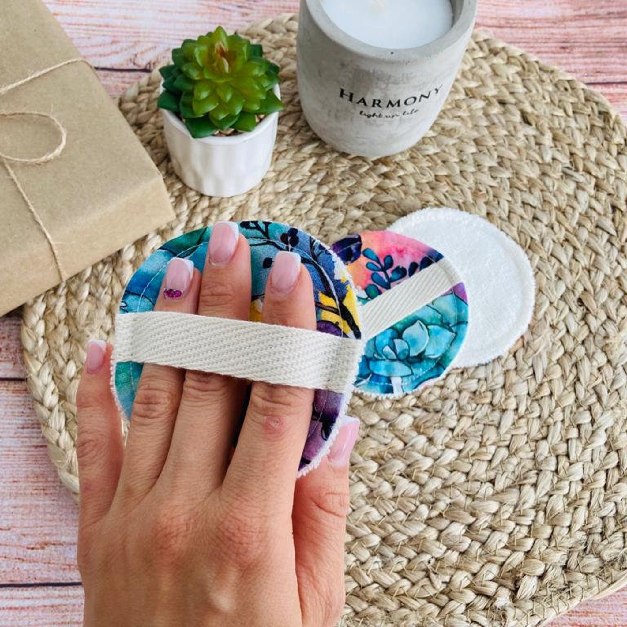 Reusable makeup remover pads with floral print, white strap, and cotton material held by hand