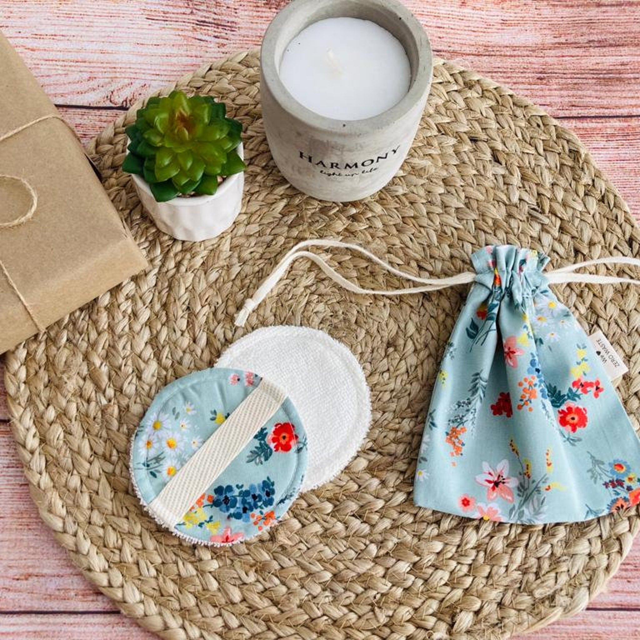 Reusable facial rounds with floral print, white fabric, and drawstring bag on woven mat