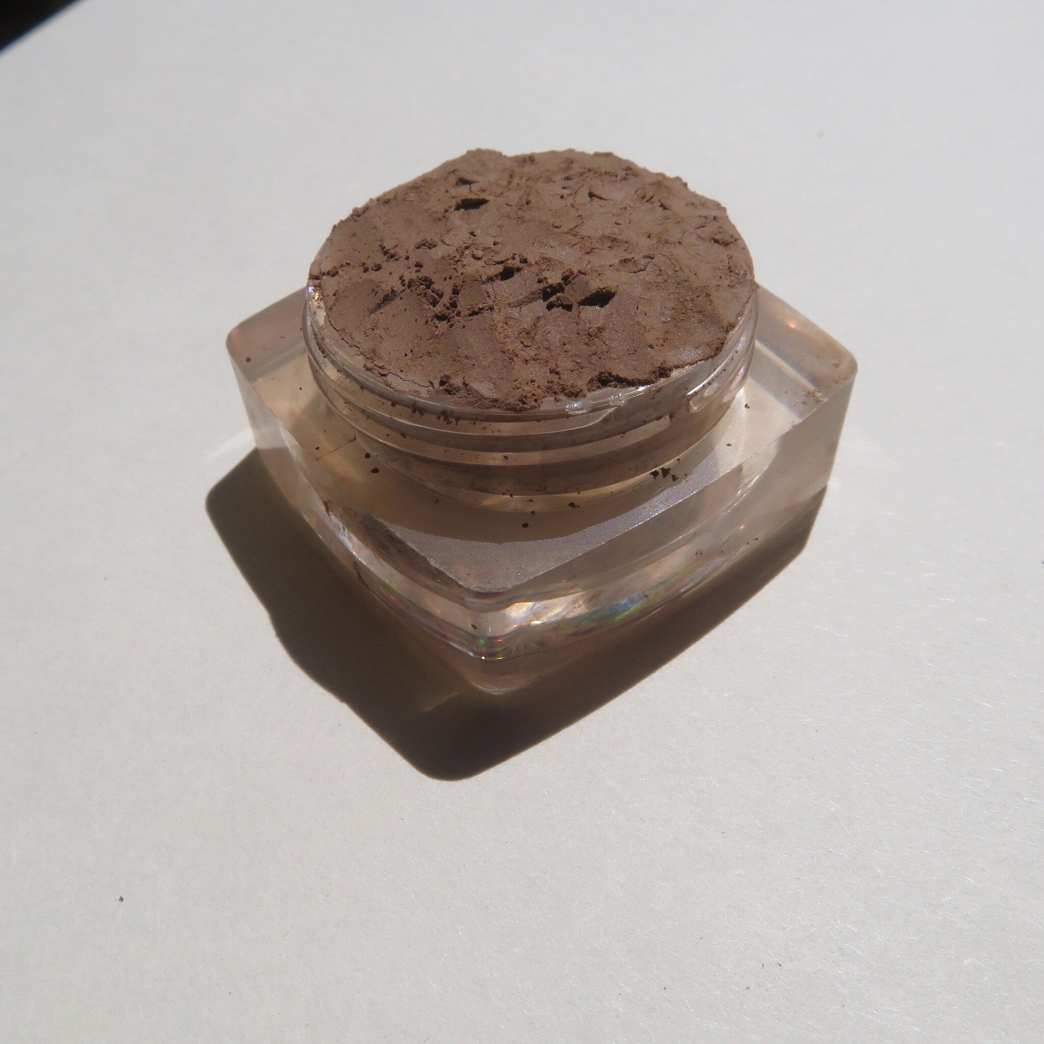Side view of loose mineral eyeshadow in matte brown shade with eco-friendly packaging and sifter dispenser