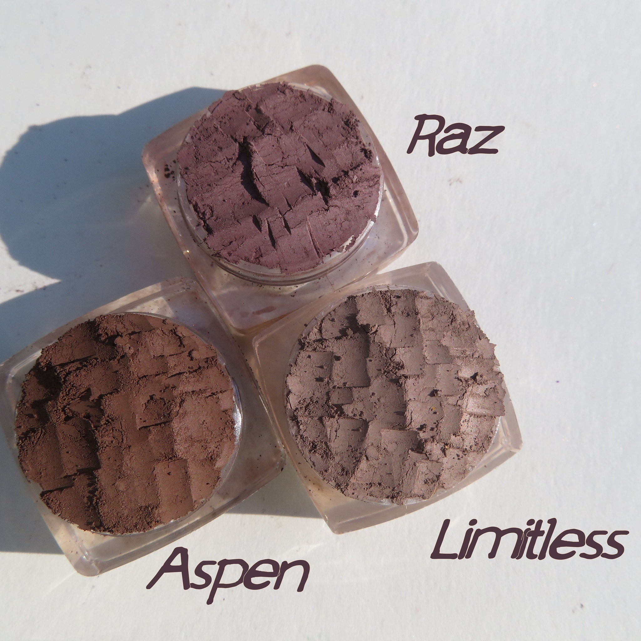 Hand applying matte brown loose pigment eyeshadow with a brush, showcasing smooth blendable texture