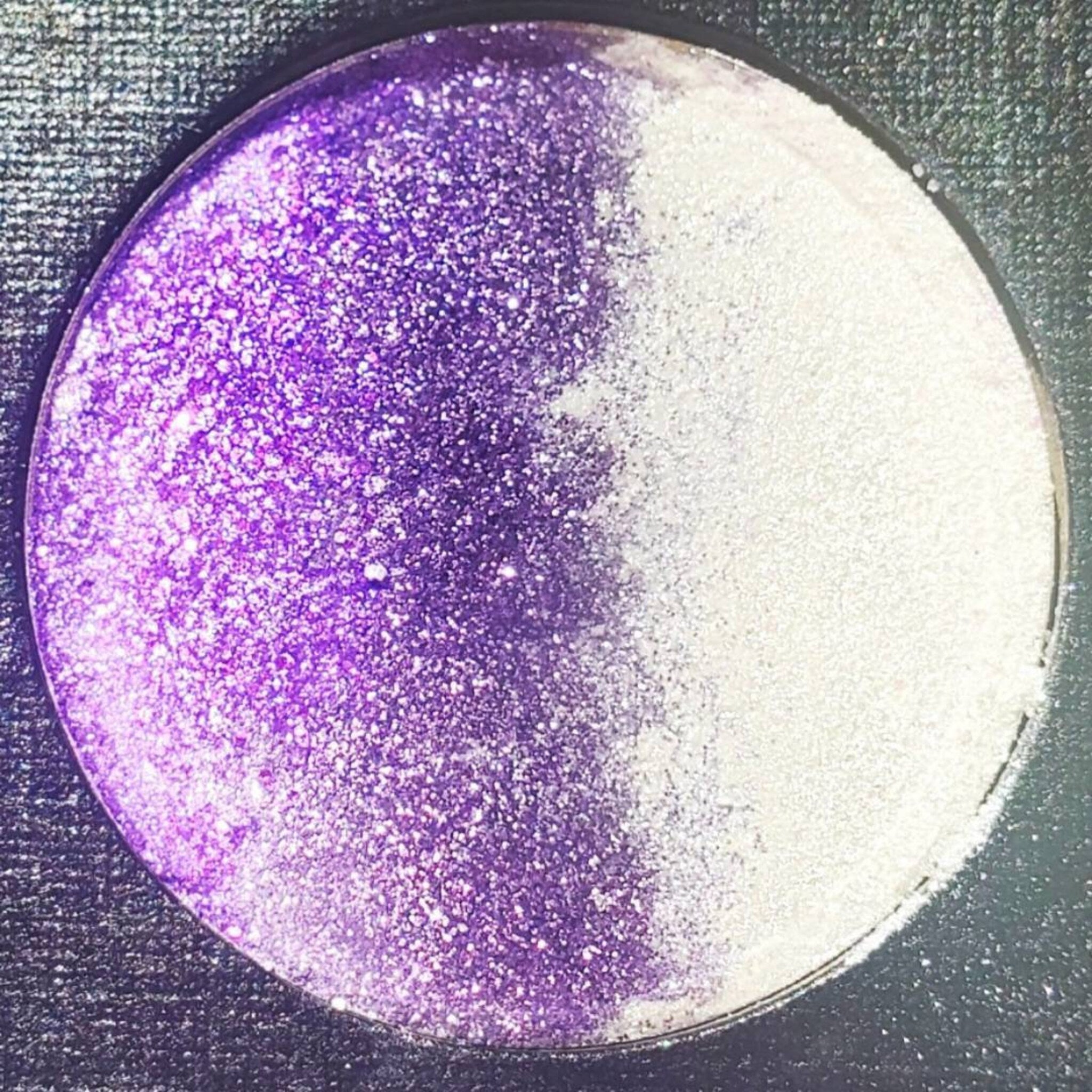 Close-up of amethyst eyeshadow palette showing shimmer shade with silver glitter particles