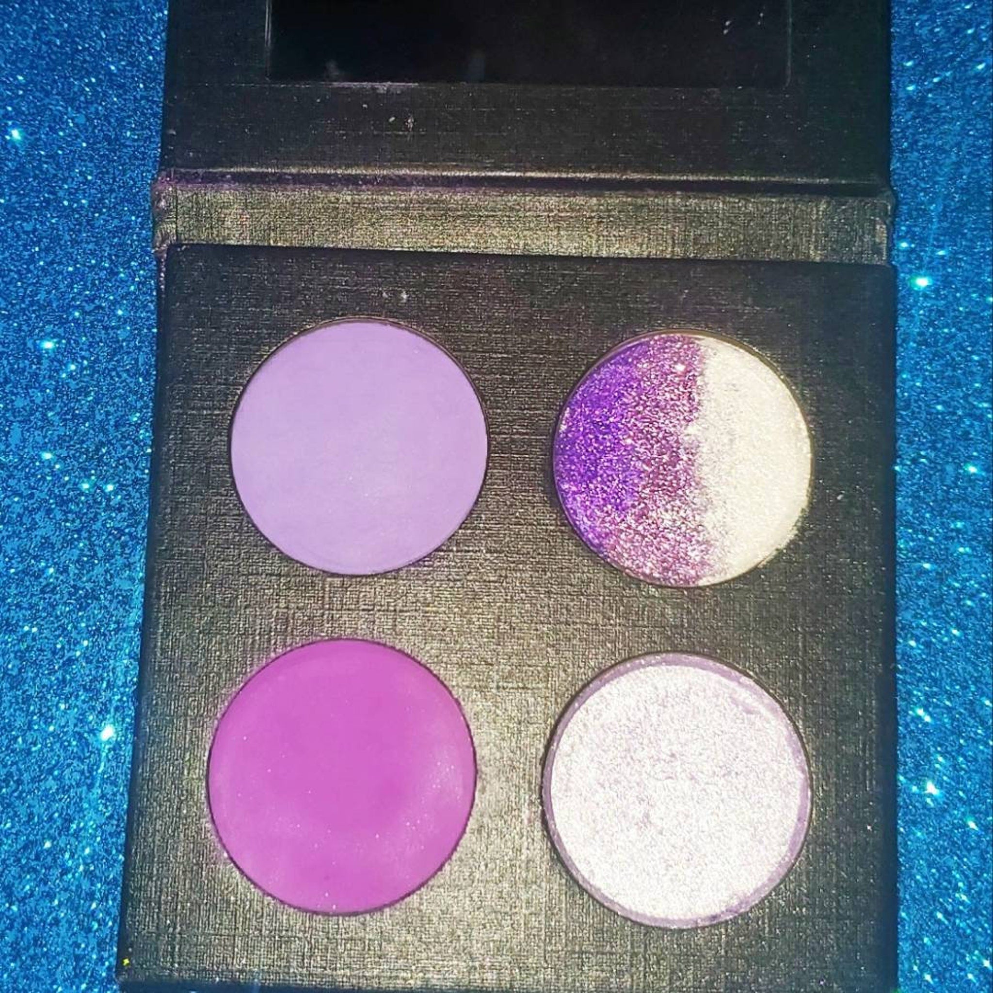 Amethyst Moon palette open with glitter shade catching light, showing violet shimmer particles