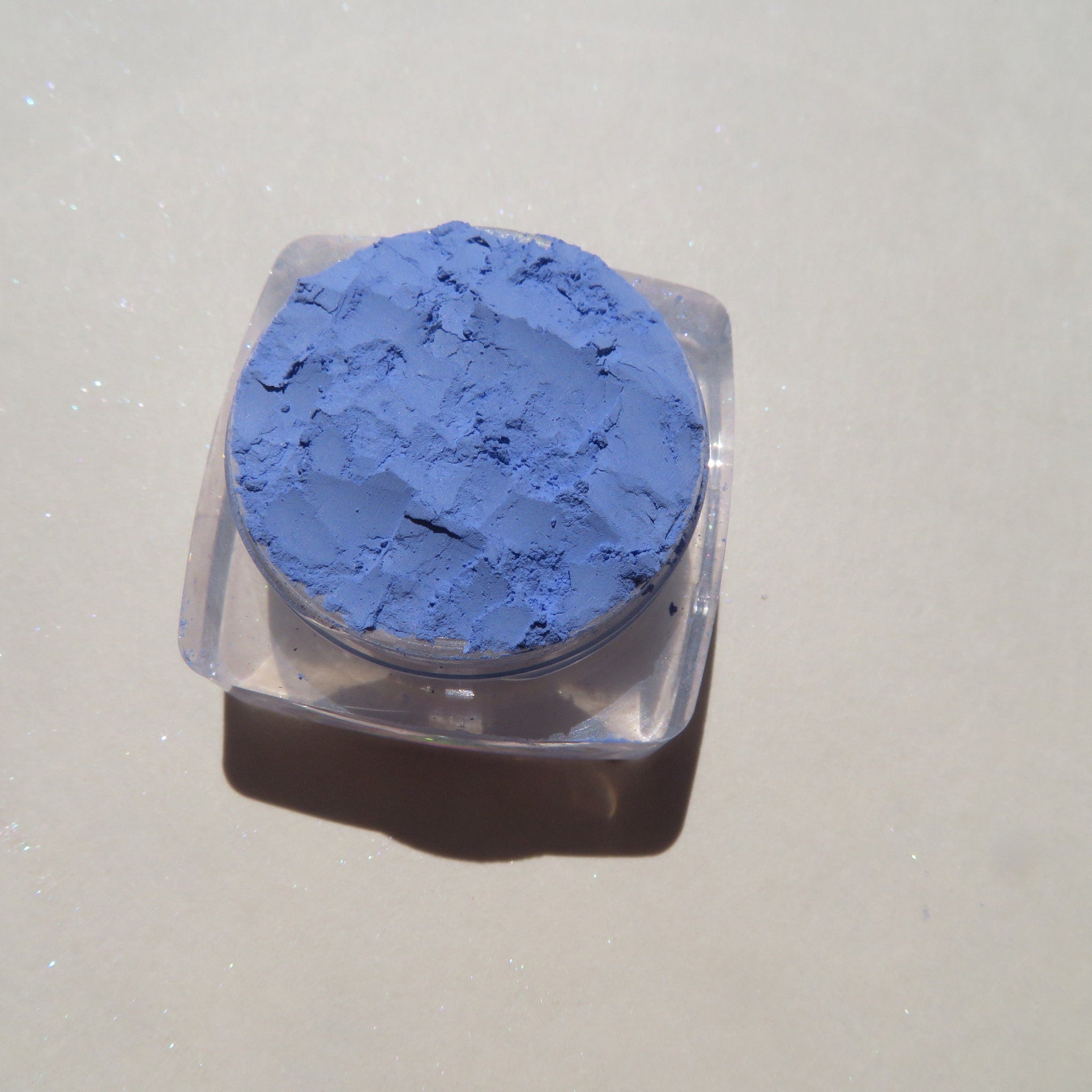 Hand applying matte sky blue mineral eyeshadow with a fluffy brush for a soft blended look