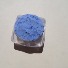 Hand applying matte sky blue mineral eyeshadow with a fluffy brush for a soft blended look