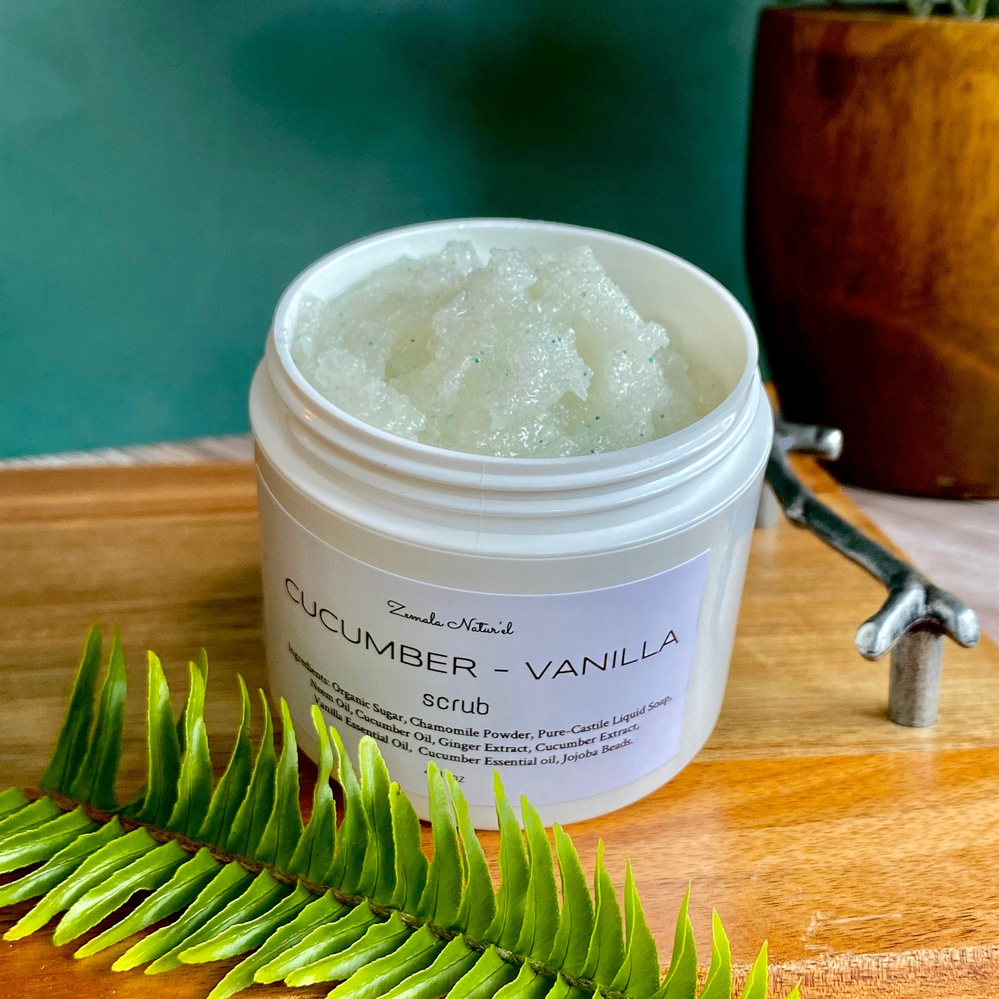 Cucumber vanilla scrub in a white jar with green granules, Zemala Naturel label on wood surface