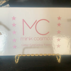 Glitter eye shadow palette with six vibrant shades in gold, pink, and blue hues, arranged in circular pans.