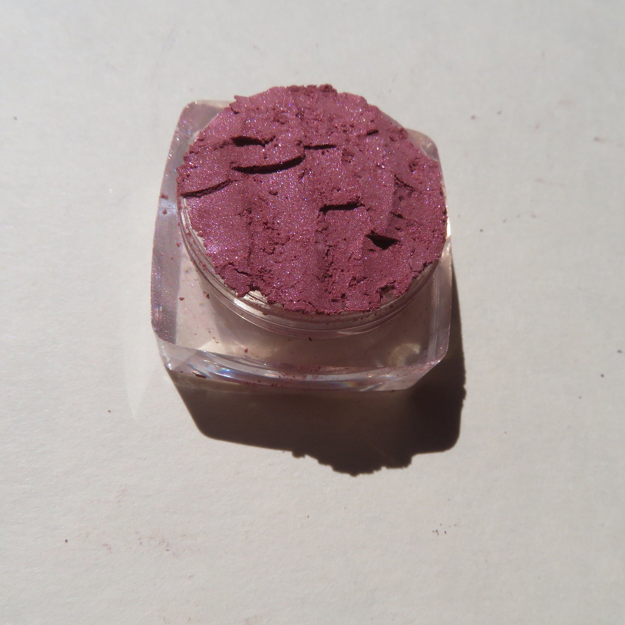Side view of CHLOE Vegan Mineral Eyeshadow pot showing loose dark pink shimmer powder with cruelty-free label