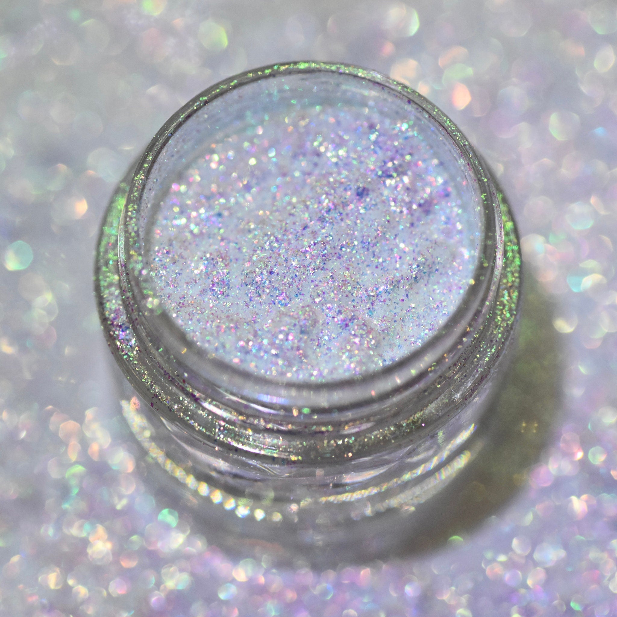 Close-up of sparkling multichrome loose powder eyeshadow shifting between silver, blue, and purple hues