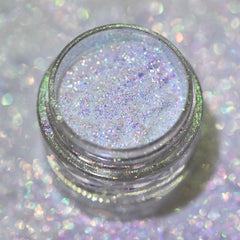 Close-up of sparkling multichrome loose powder eyeshadow shifting between silver, blue, and purple hues