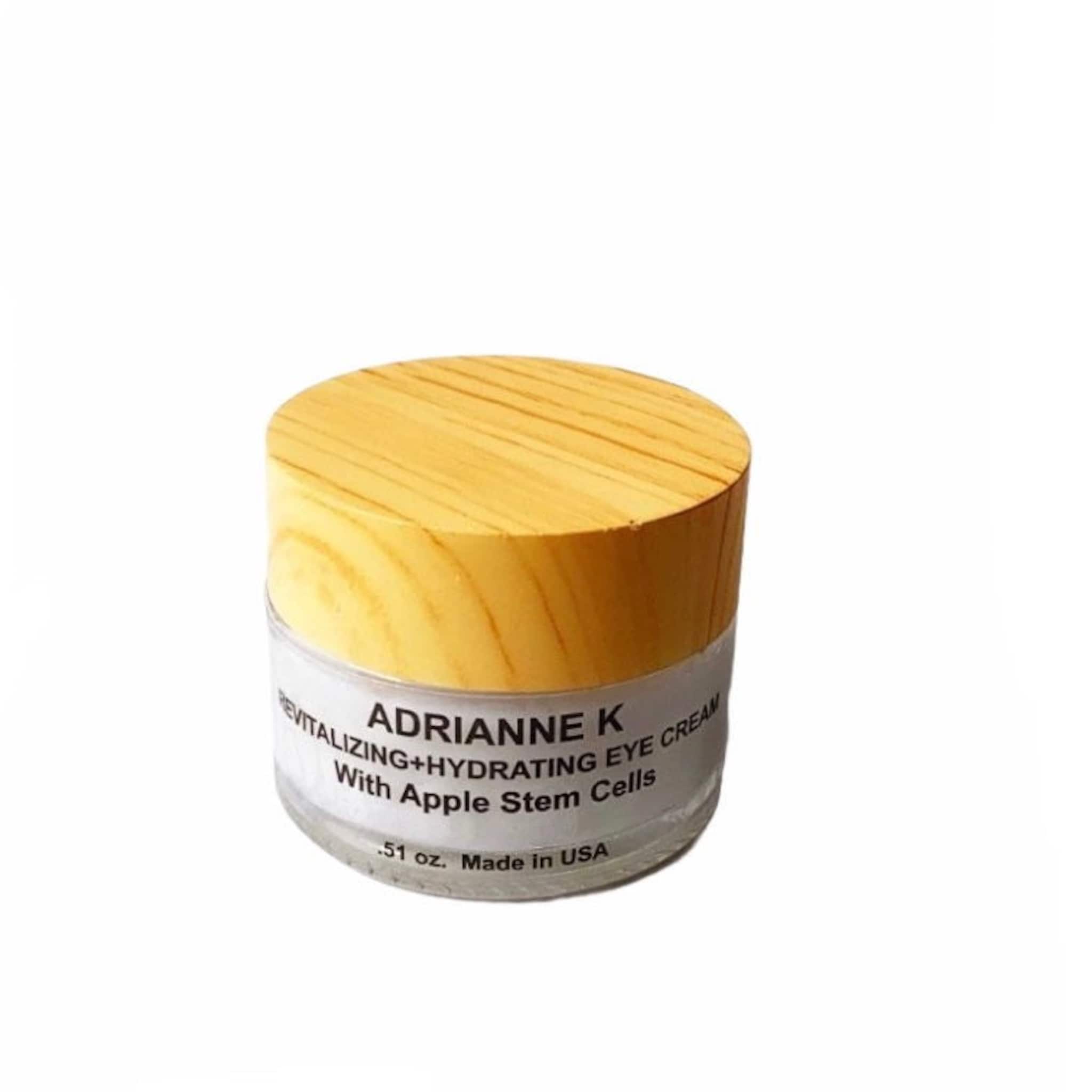 Eye cream jar with wooden lid, white label, and brand name Adrianne K visible