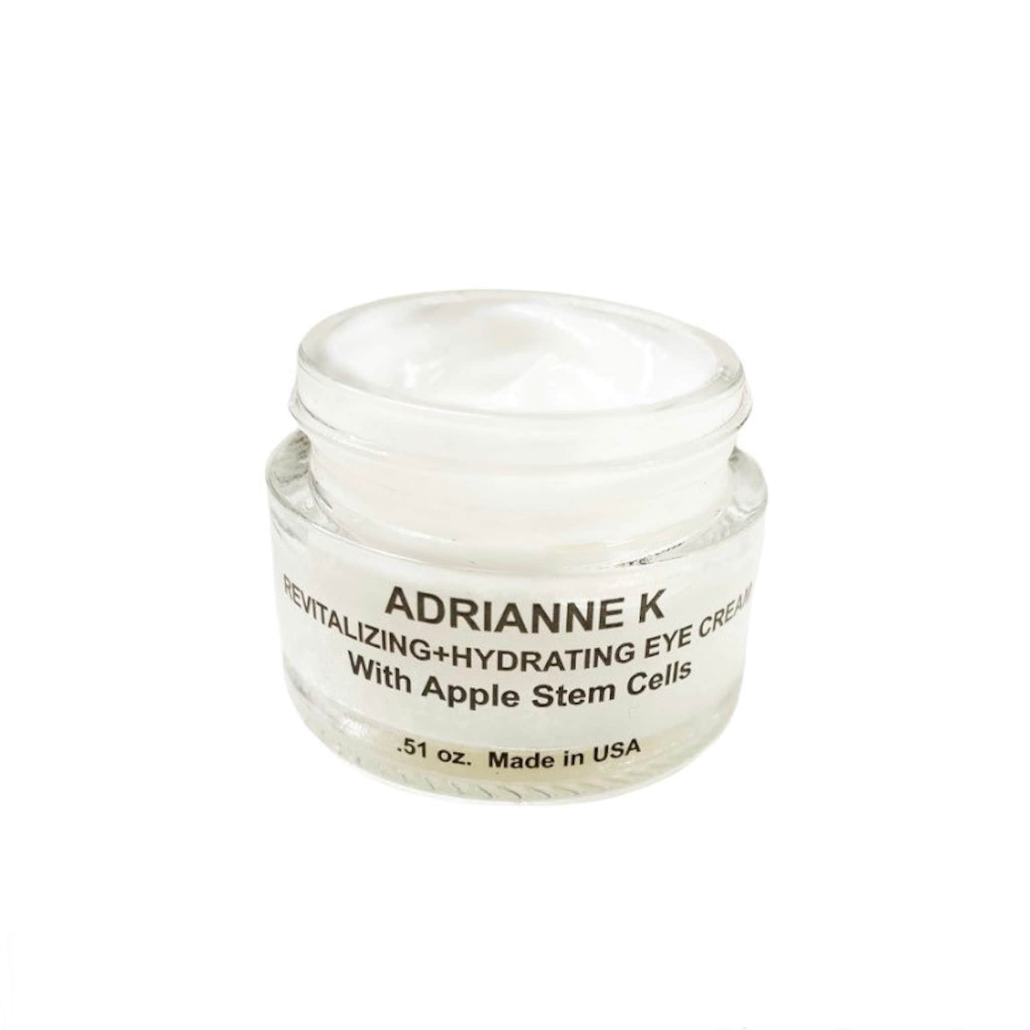 Eye cream jar with white cream, clear glass, and brand text "ADRIANNE K" visible