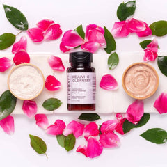 Facial Cleanser powder with Ora's Amazing Herbal bottle, pink rose petals, and wooden bowls on white surface