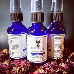 Face tonic bottles with blue glass, black caps, and white labels, "Le Noir Bleu" brand