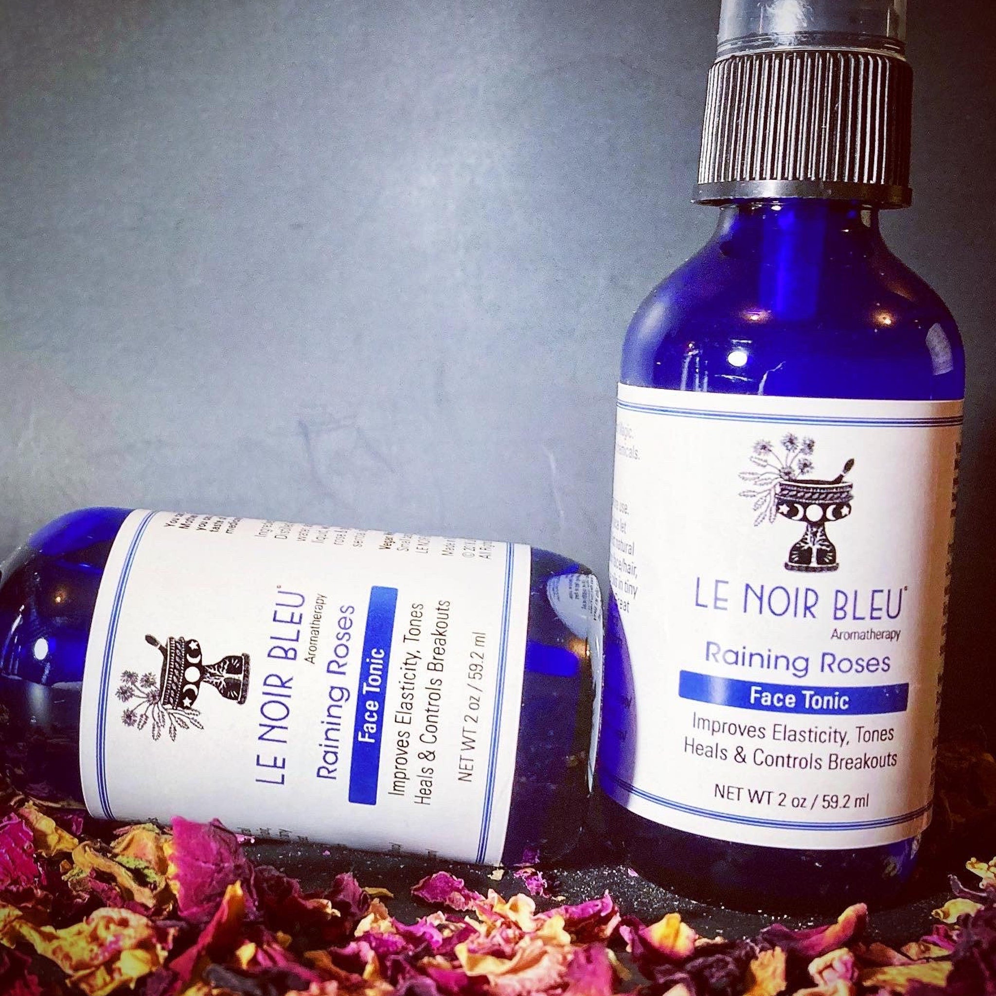 Face tonic bottles with blue glass, black caps, and white labels with brand text and floral design