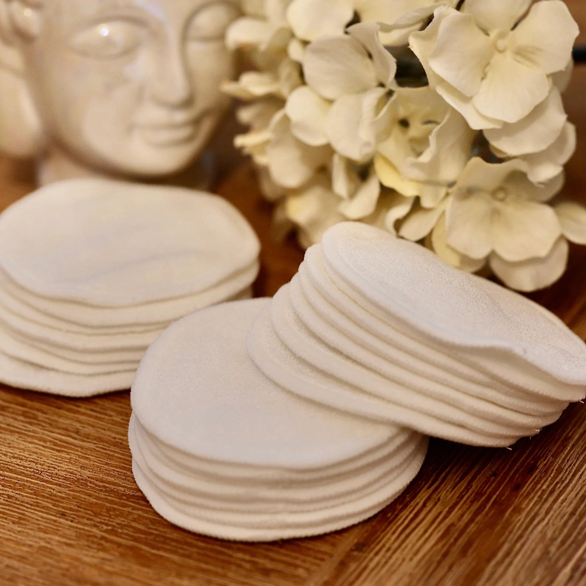 Reusable cotton pads, white circular pads, stacked on wooden surface