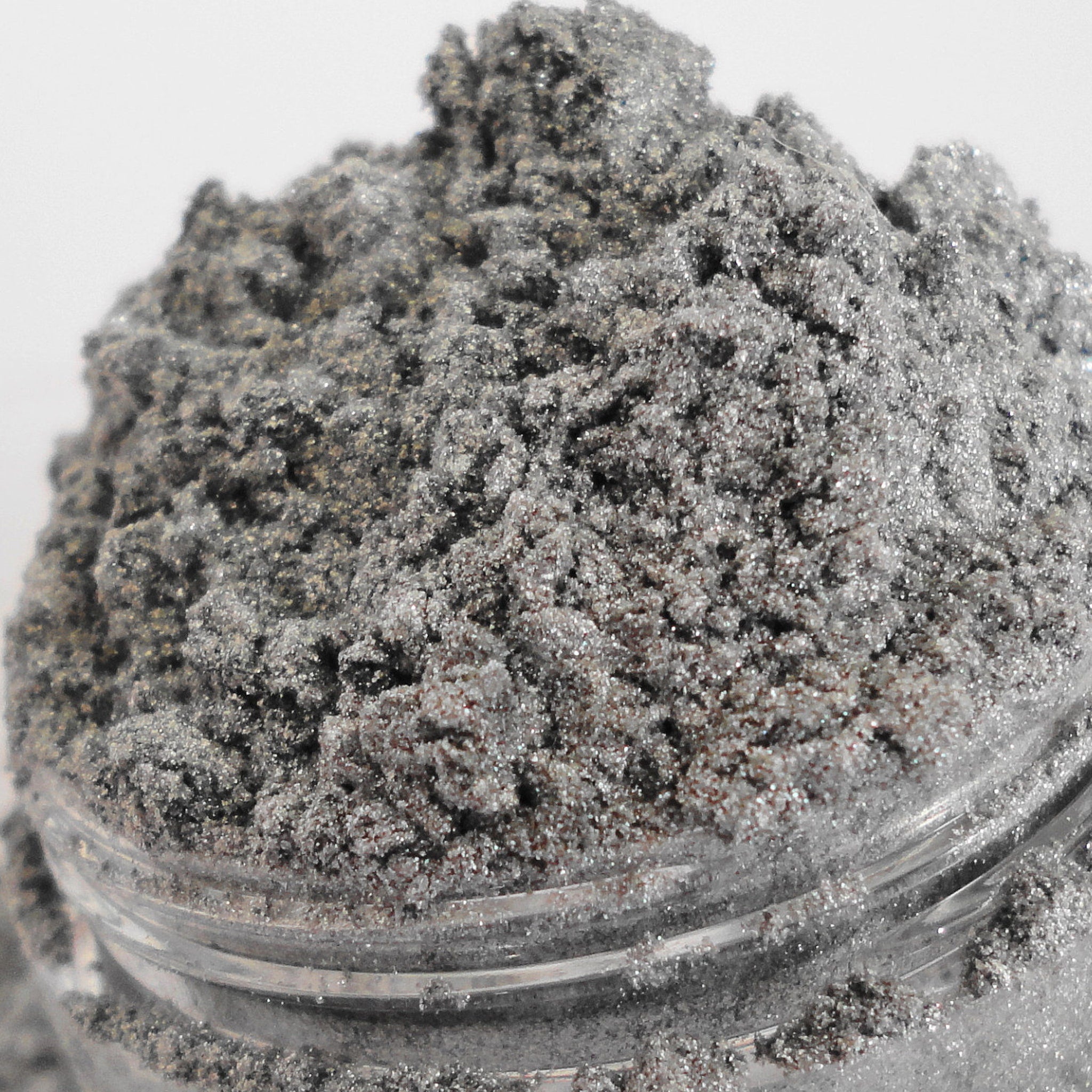 Silver glitter powder with metallic sheen in a glass jar, close-up view
