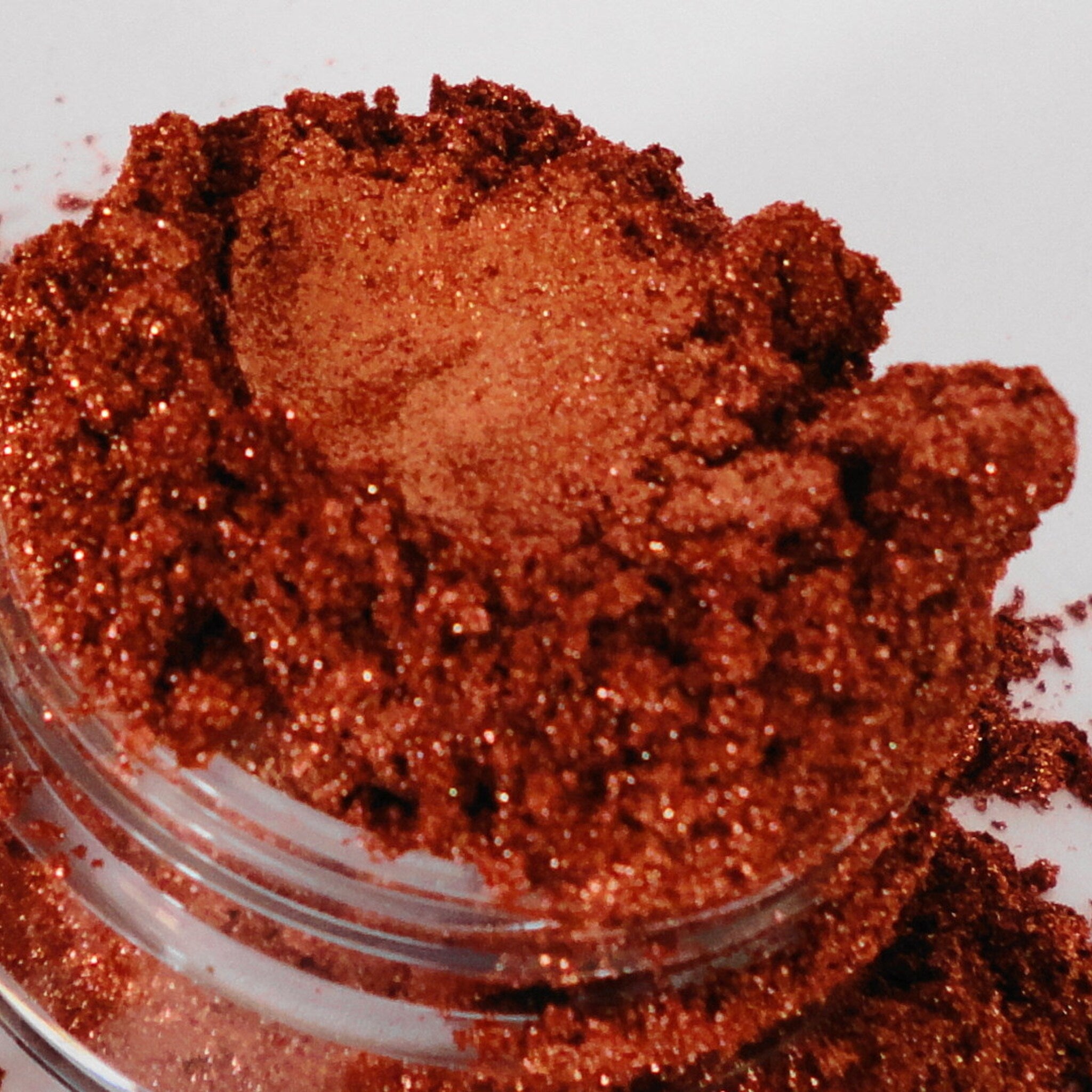 Glitter powder, reddish brown, sparkly texture, in a clear container, close up shot