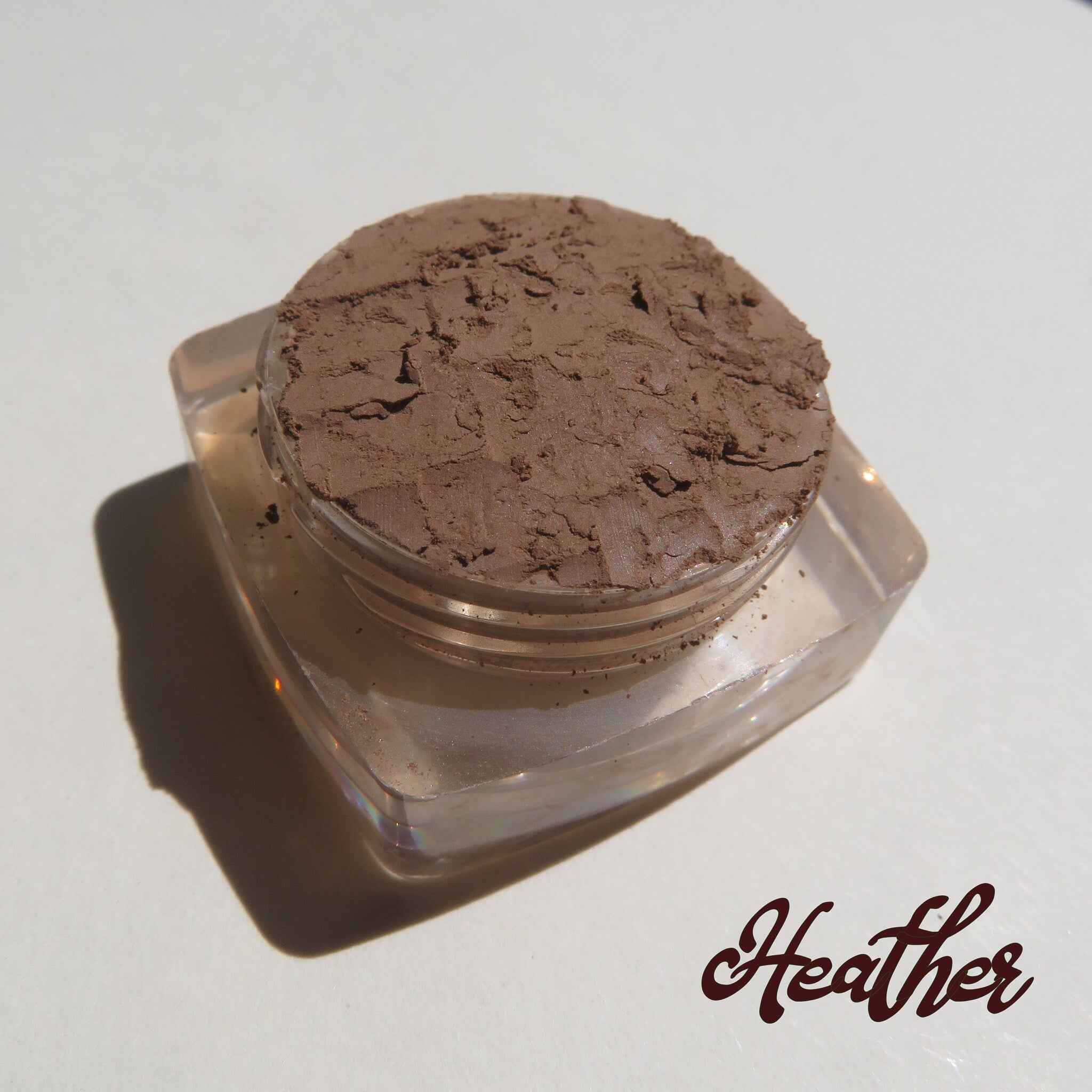 Close-up of open jar showing loose mineral eyeshadow in matte heather brown with eco-friendly packaging
