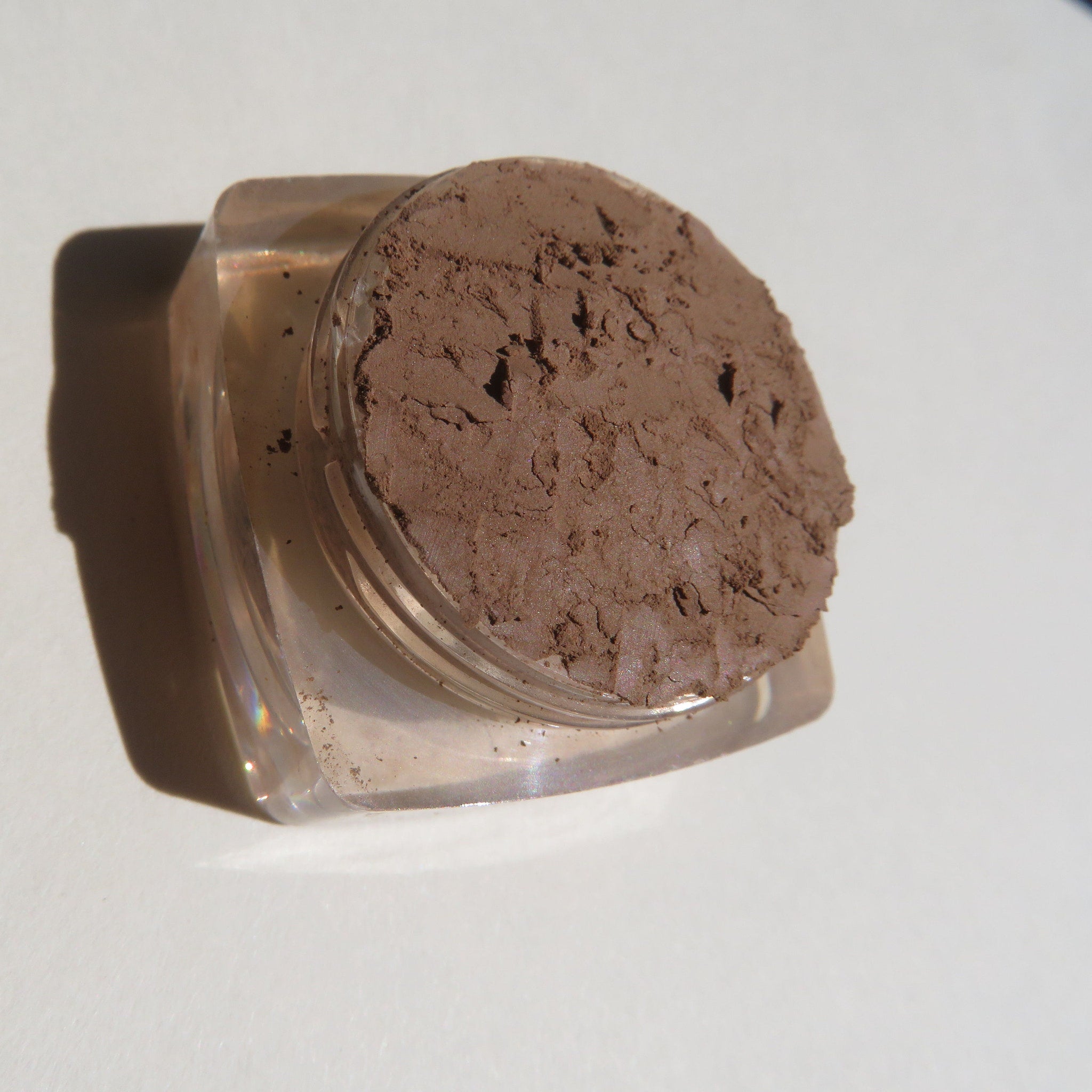 Close-up of loose mineral eyeshadow in matte medium brown shade with soft powdery texture