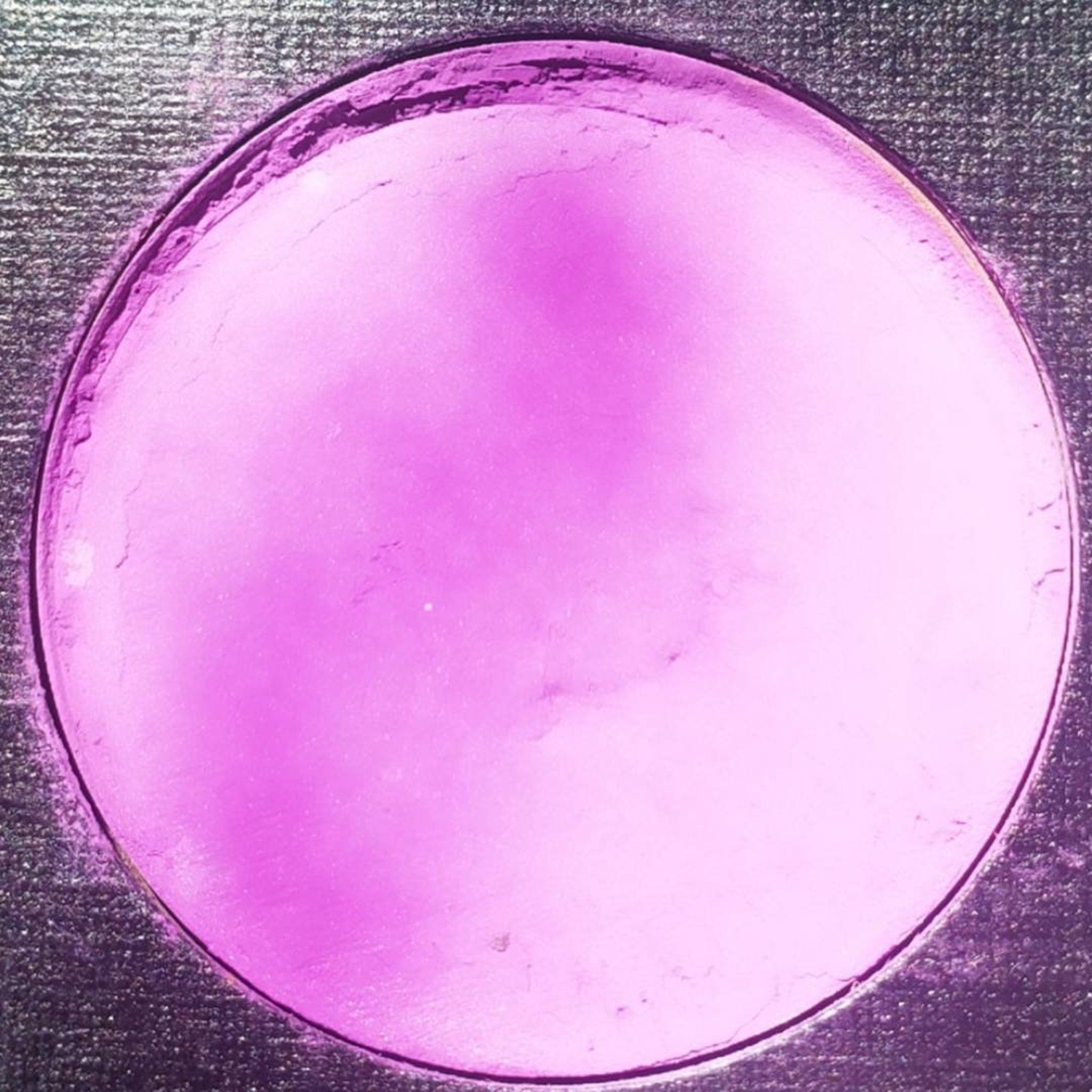 Close-up of fingertips applying shimmery purple eyeshadow from palette to eyelid