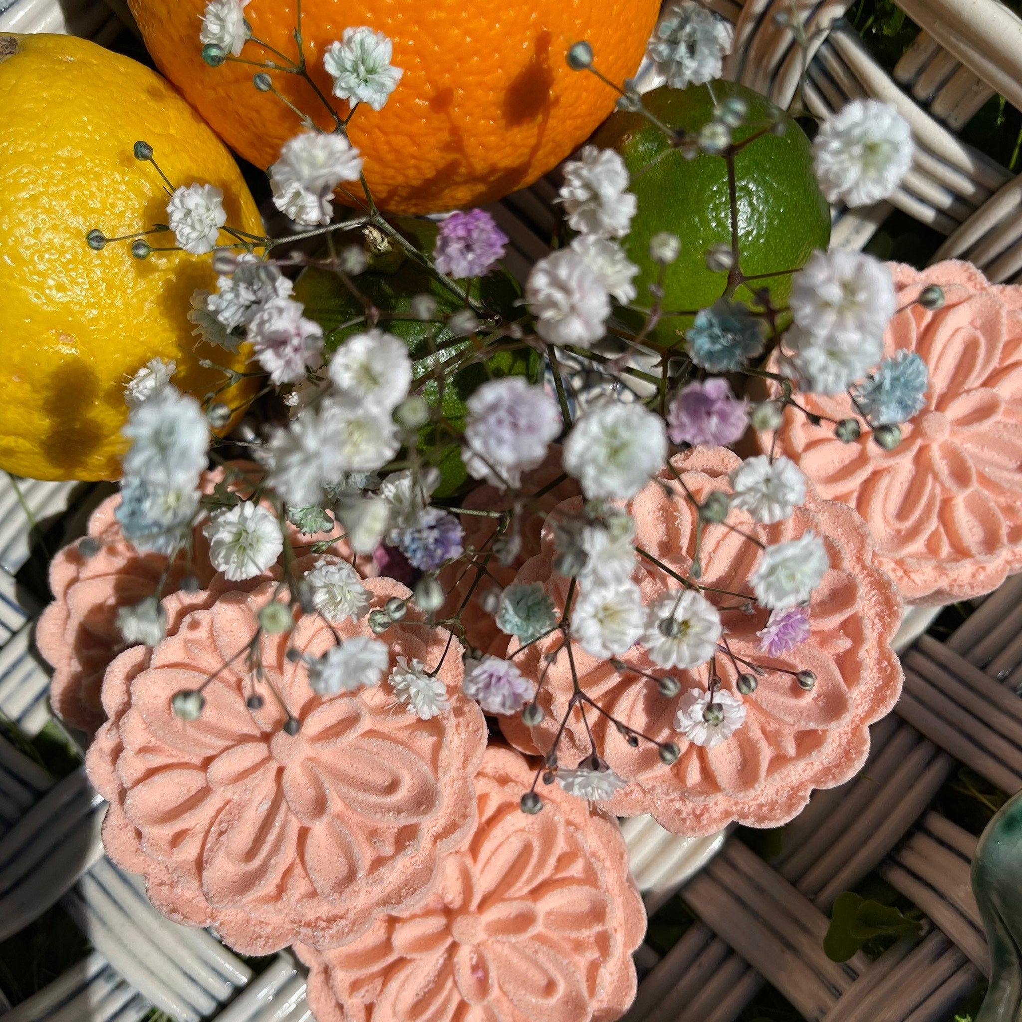Pink floral cookies with white flowers, orange, lemon, and lime on a woven basket