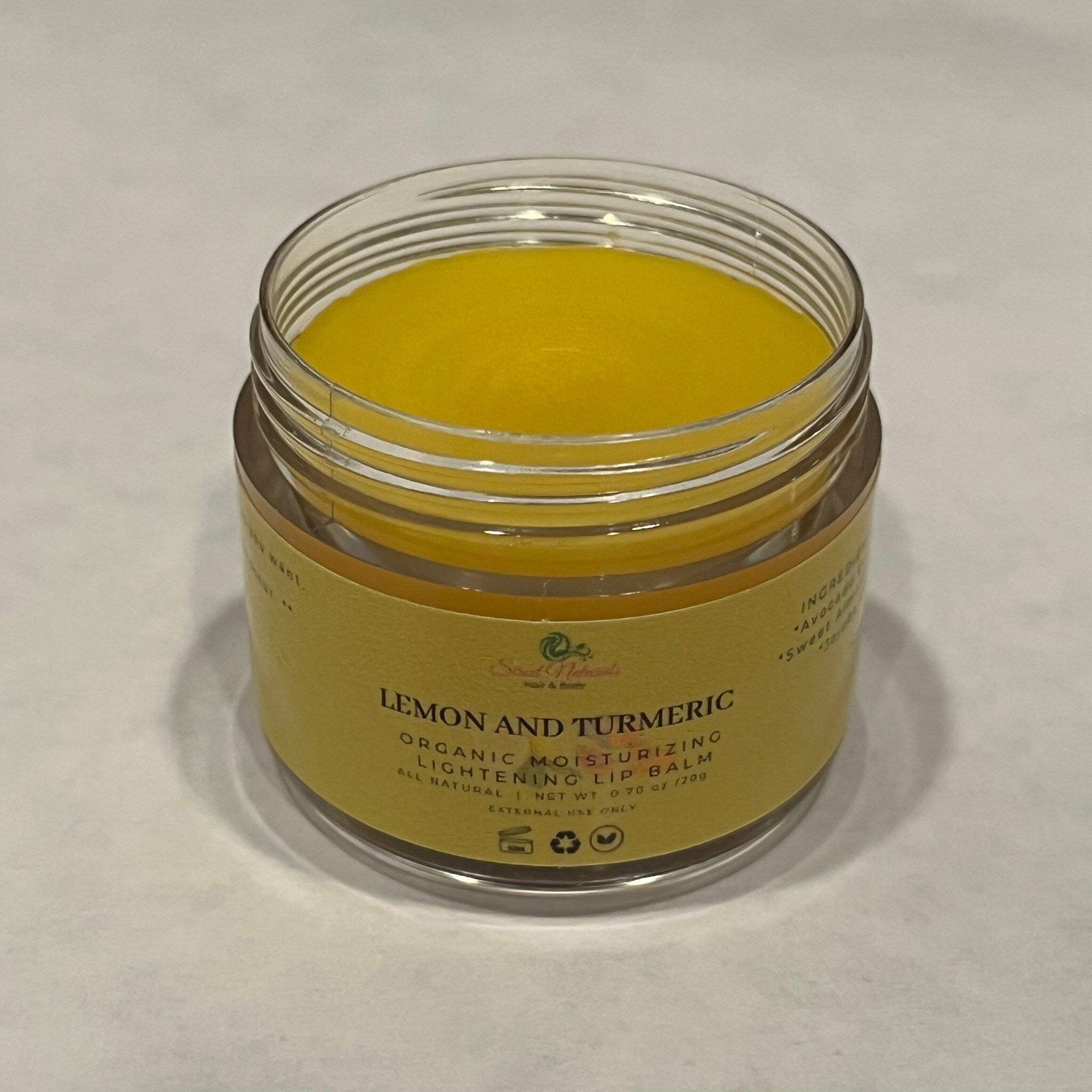 Lip balm in a clear glass jar with yellow balm and a yellow label with text