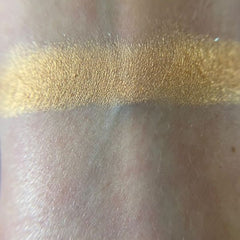 Close-up of fingertips applying shimmery taupe eyeshadow to eyelid with soft blending motion