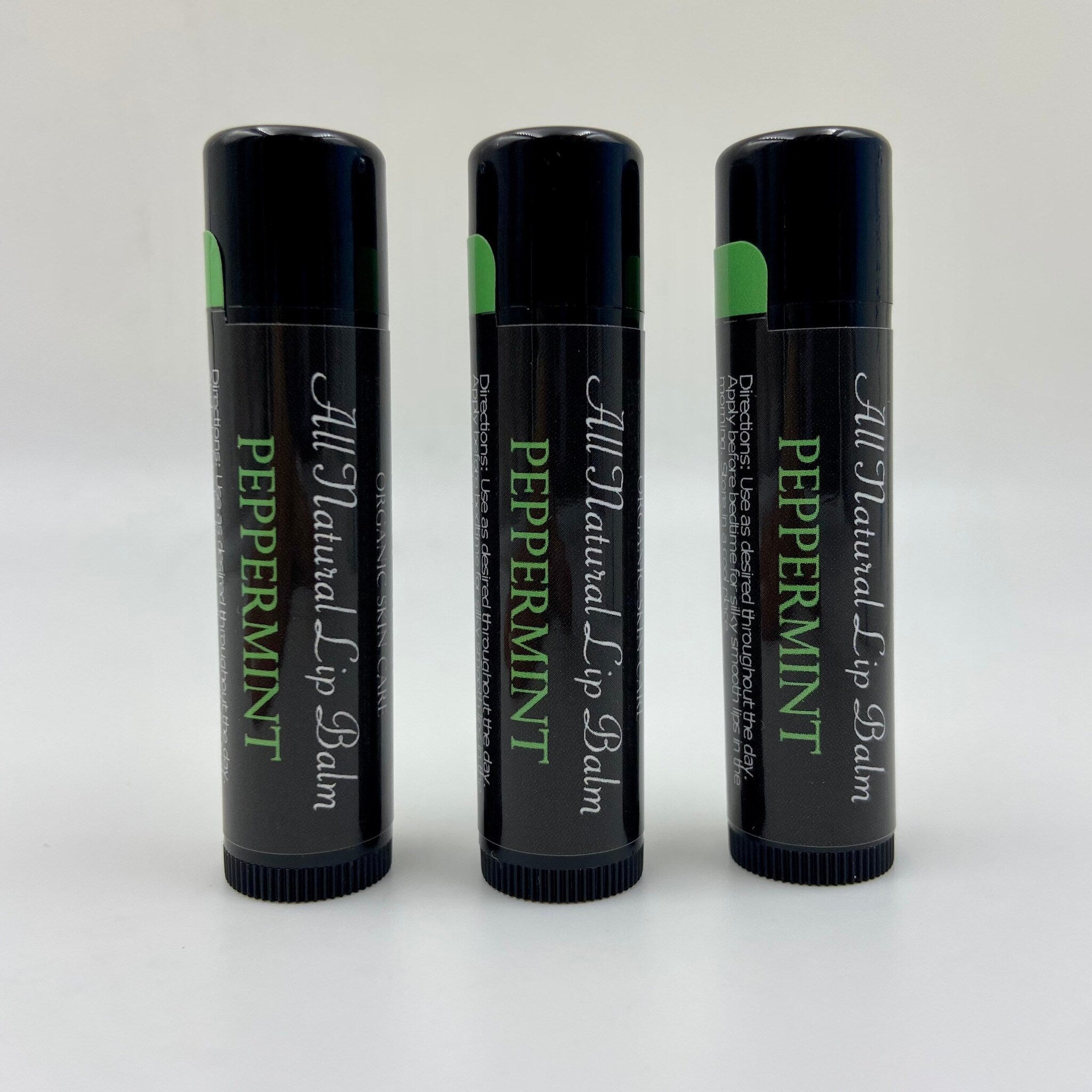 Lip balm tubes, black with green accents, Levs Naturals Peppermint text visible