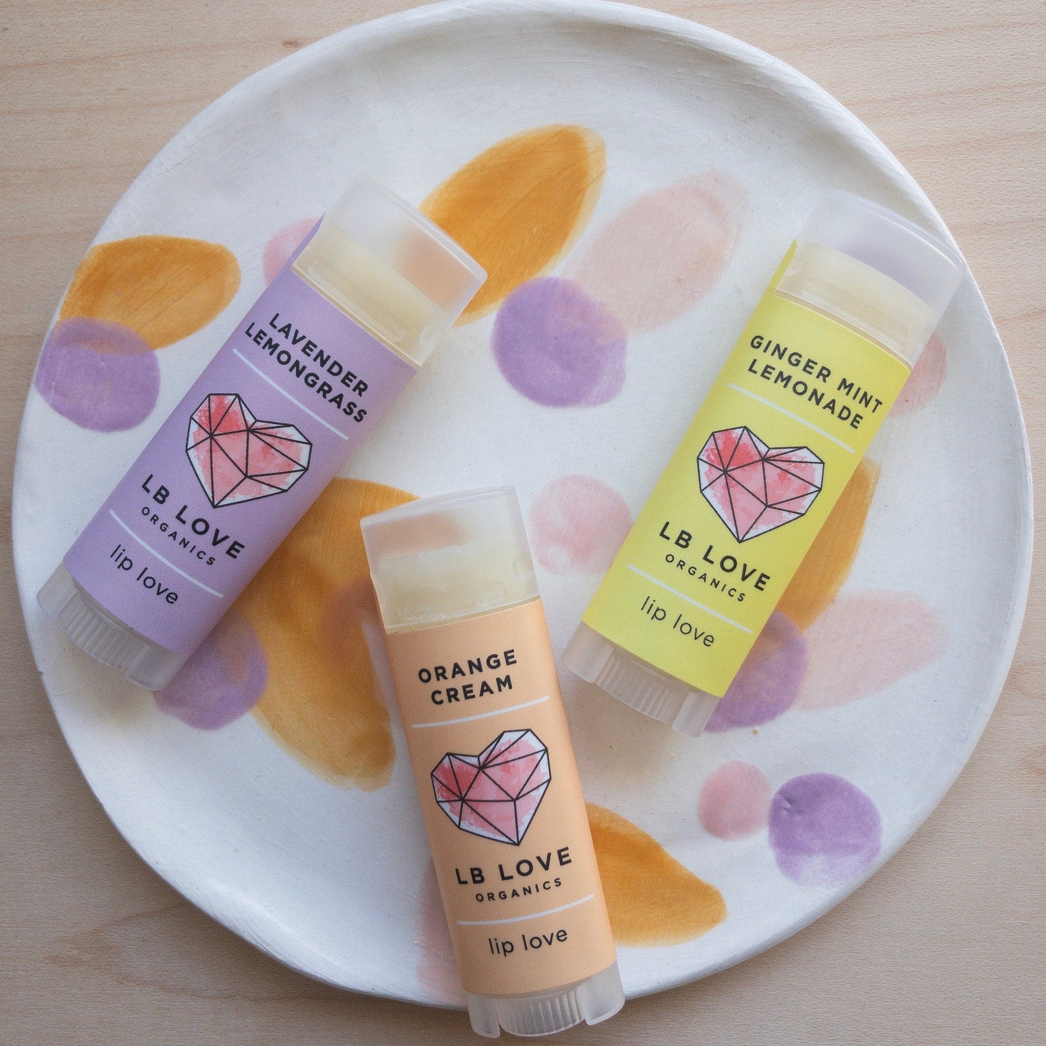 Lip balm tubes in various colors with LB Love branding on a patterned plate