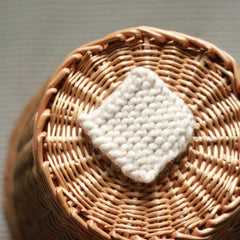 Woven basket with cream knitted square, natural brown wicker material, overhead view