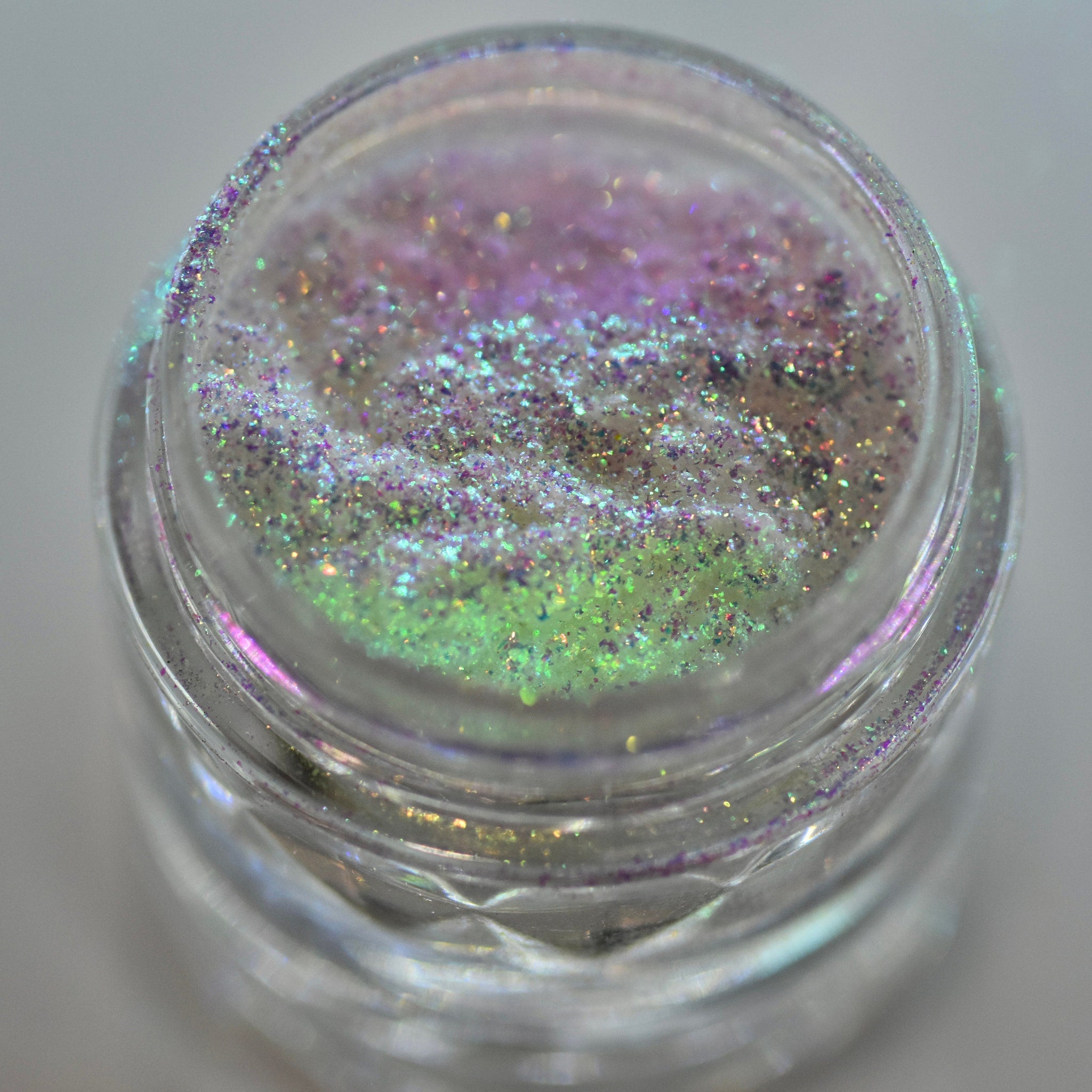 Glass jar of loose powder eyeshadow in shifting iridescent silver with holographic moon dust shimmer