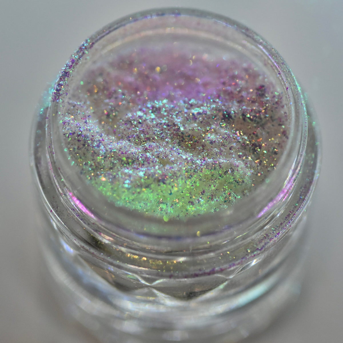 Glass jar of loose powder eyeshadow in shifting iridescent silver with holographic moon dust shimmer