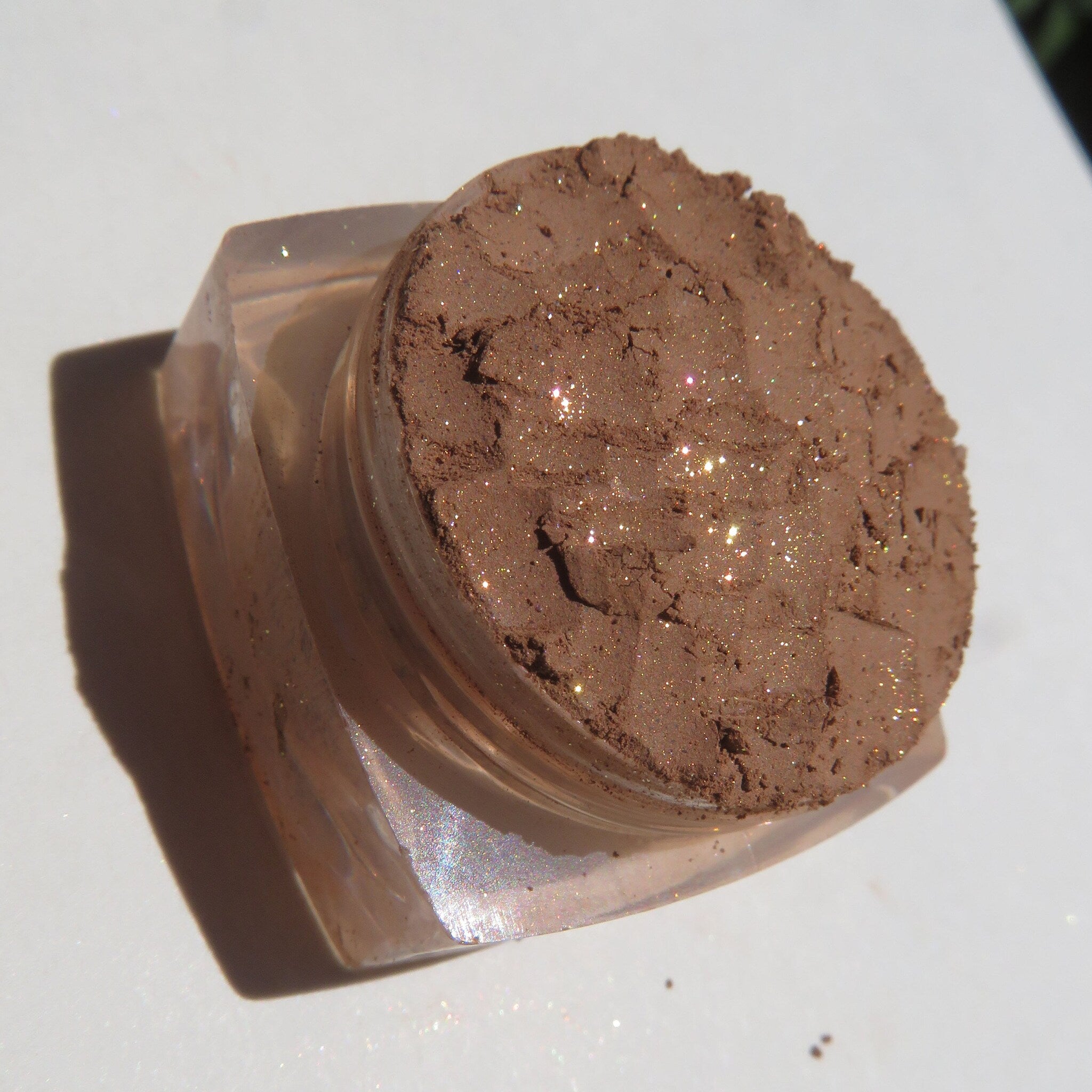 Hand applying golden brown shimmer loose powder eyeshadow with a fluffy brush for a soft, blended look