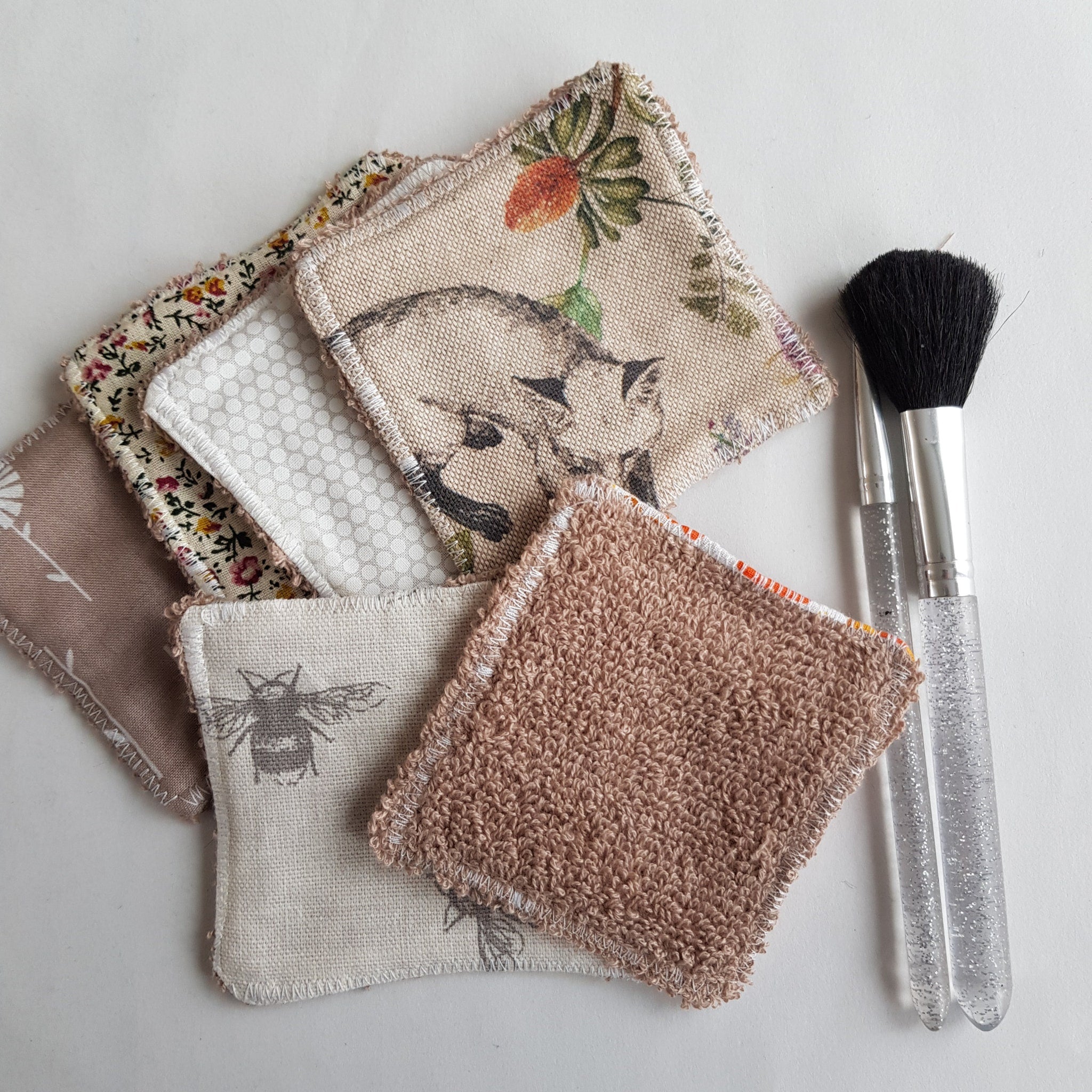 Reusable makeup remover pads with various patterns, textures, and colors, with makeup brushes