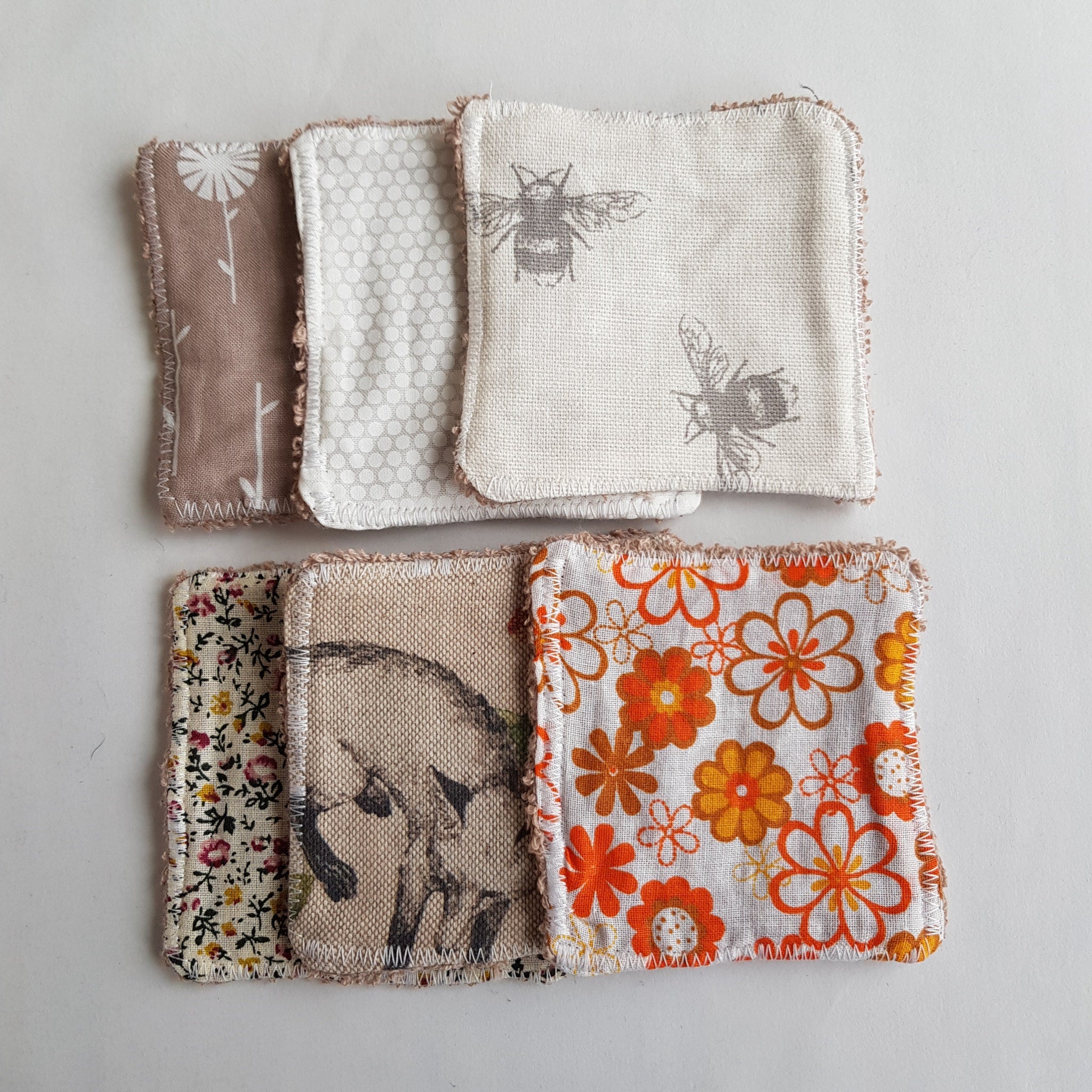 Reusable fabric squares with floral, bee, and dot patterns in brown, white, and orange colors