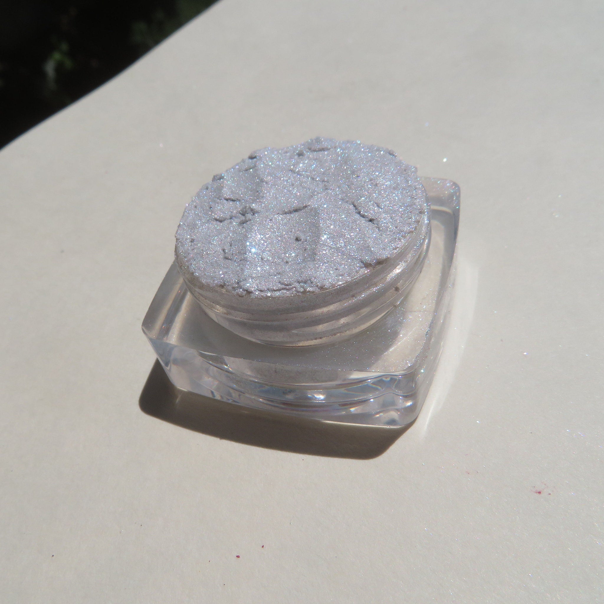 Hand applying loose white and silver glitter eye shadow pigments with fingertip for a sparkling makeup look