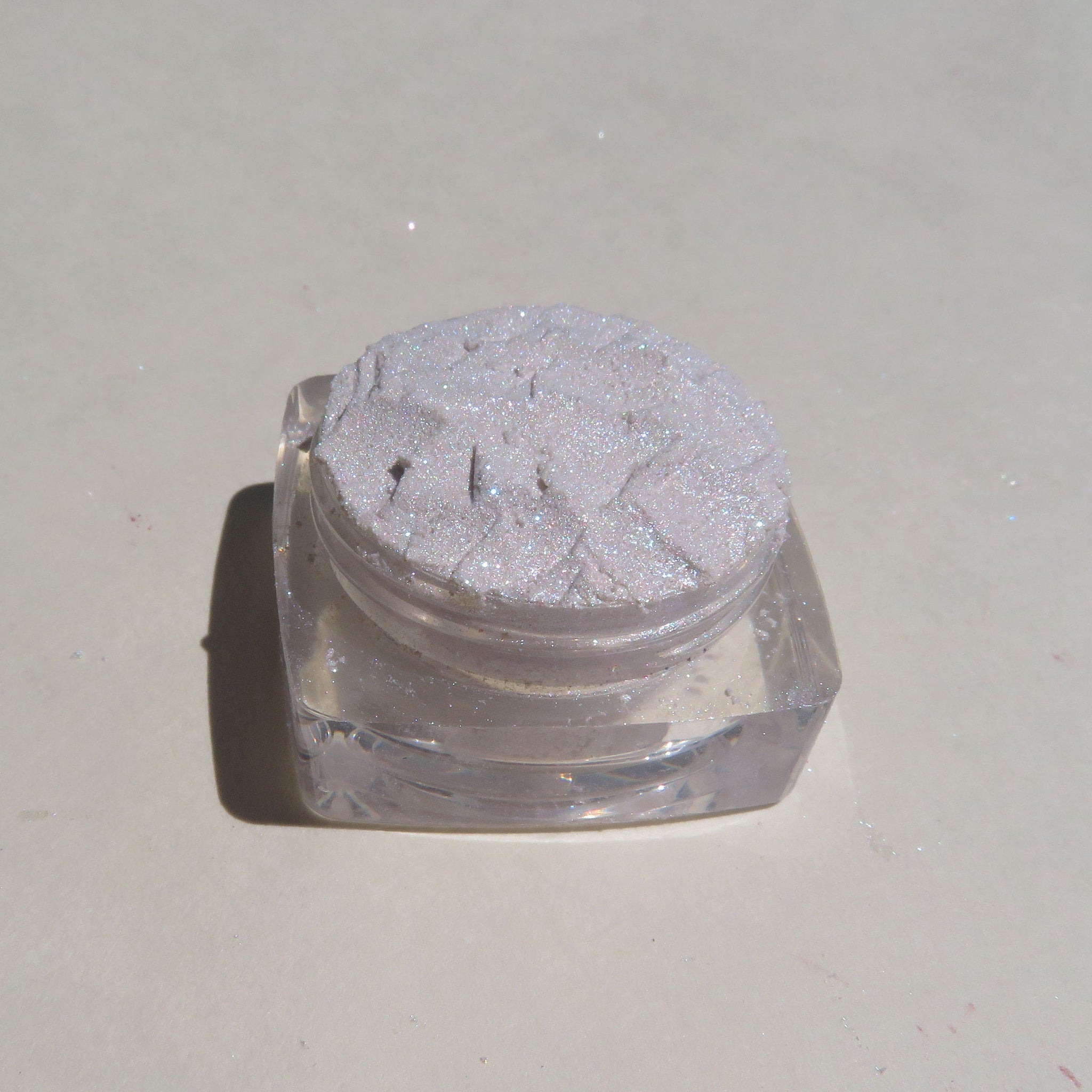 Side view of two loose pigment jars showing Super Sparkly White Rabbit and Bugs eye shadows with glitter particles