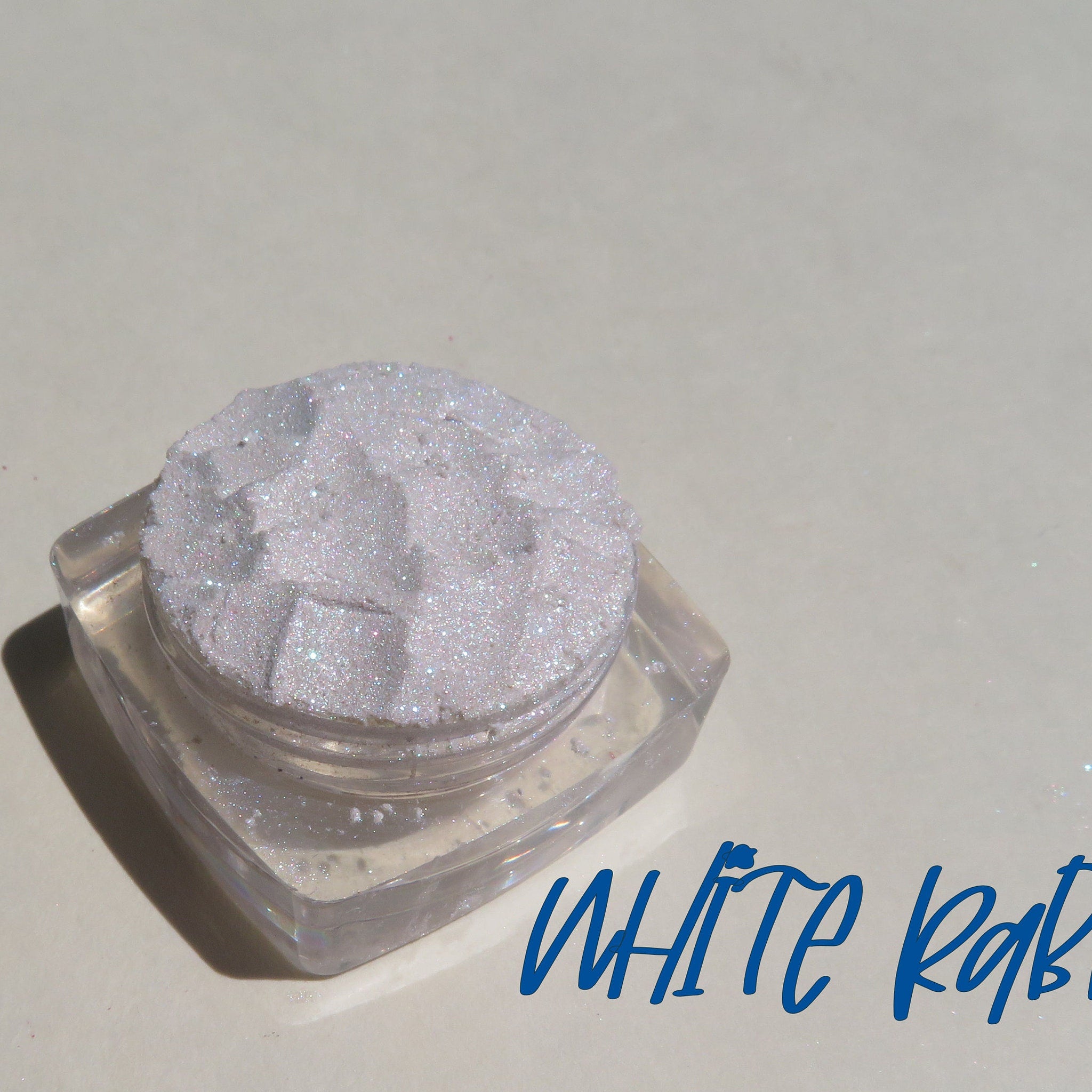 Side view of two loose glitter eyeshadows in white and silver shades with reflective sparkle particles