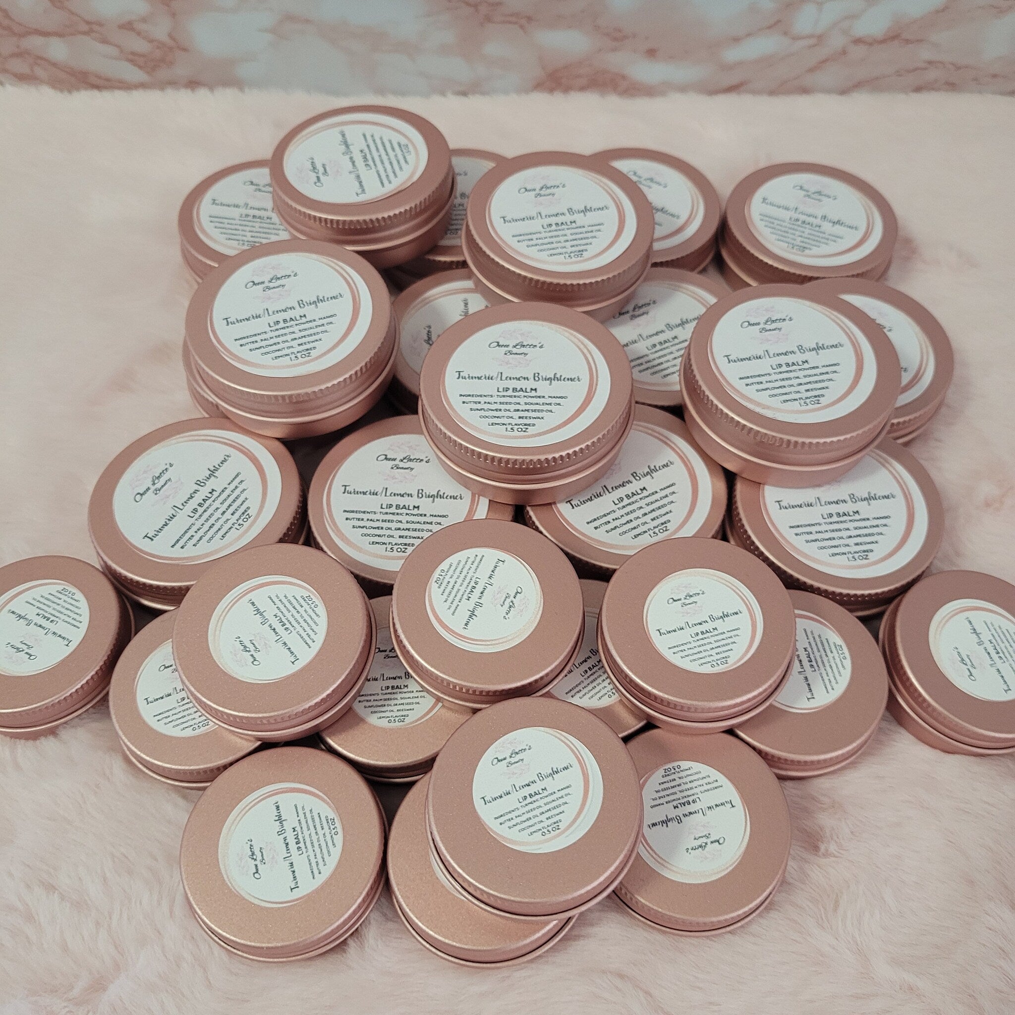 Lip balm tins, rose gold metal, white label with Ouulattesbeauty text, stacked together