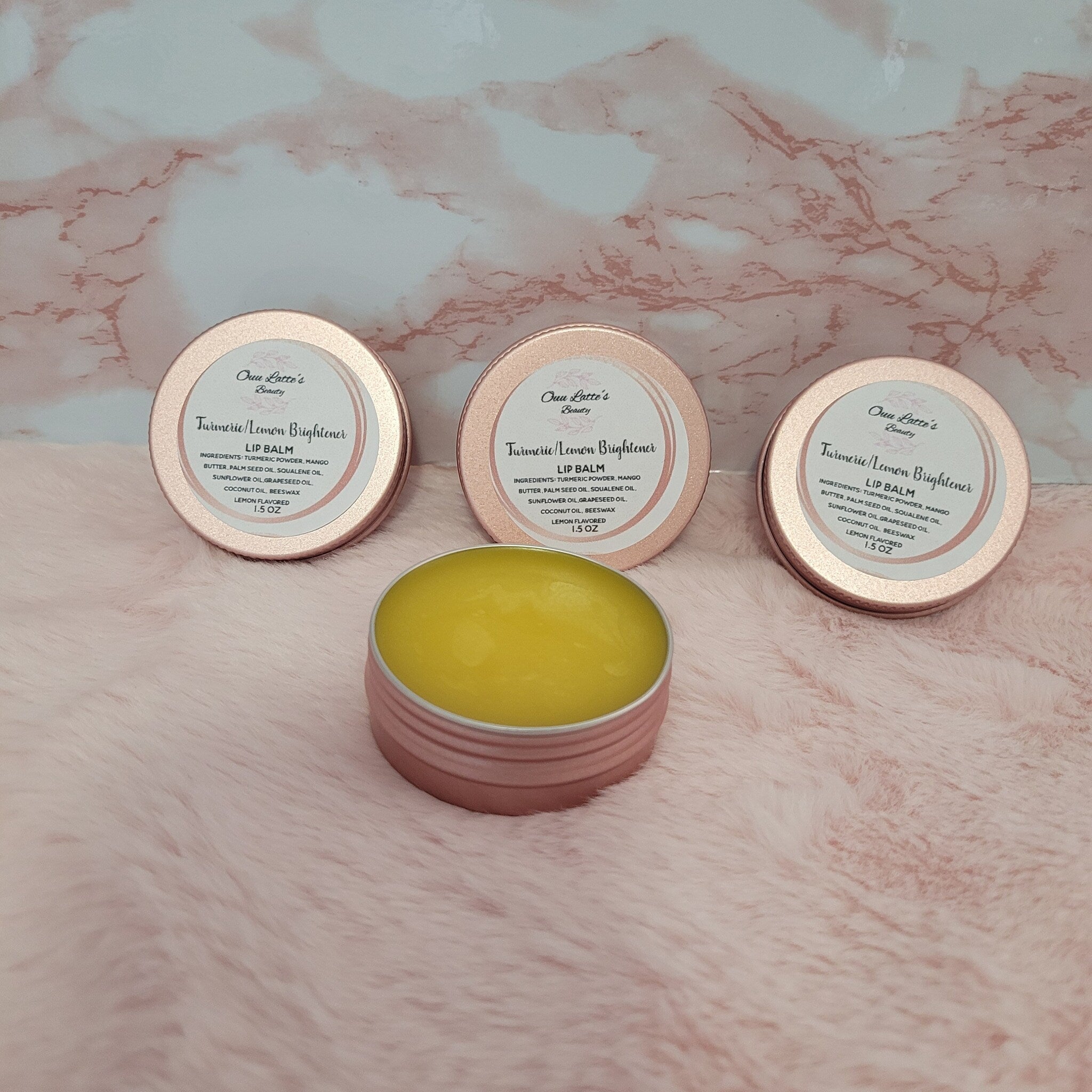 Lip balm in pink and rose gold tins with yellow balm visible, Ouu Latte's Beauty branding