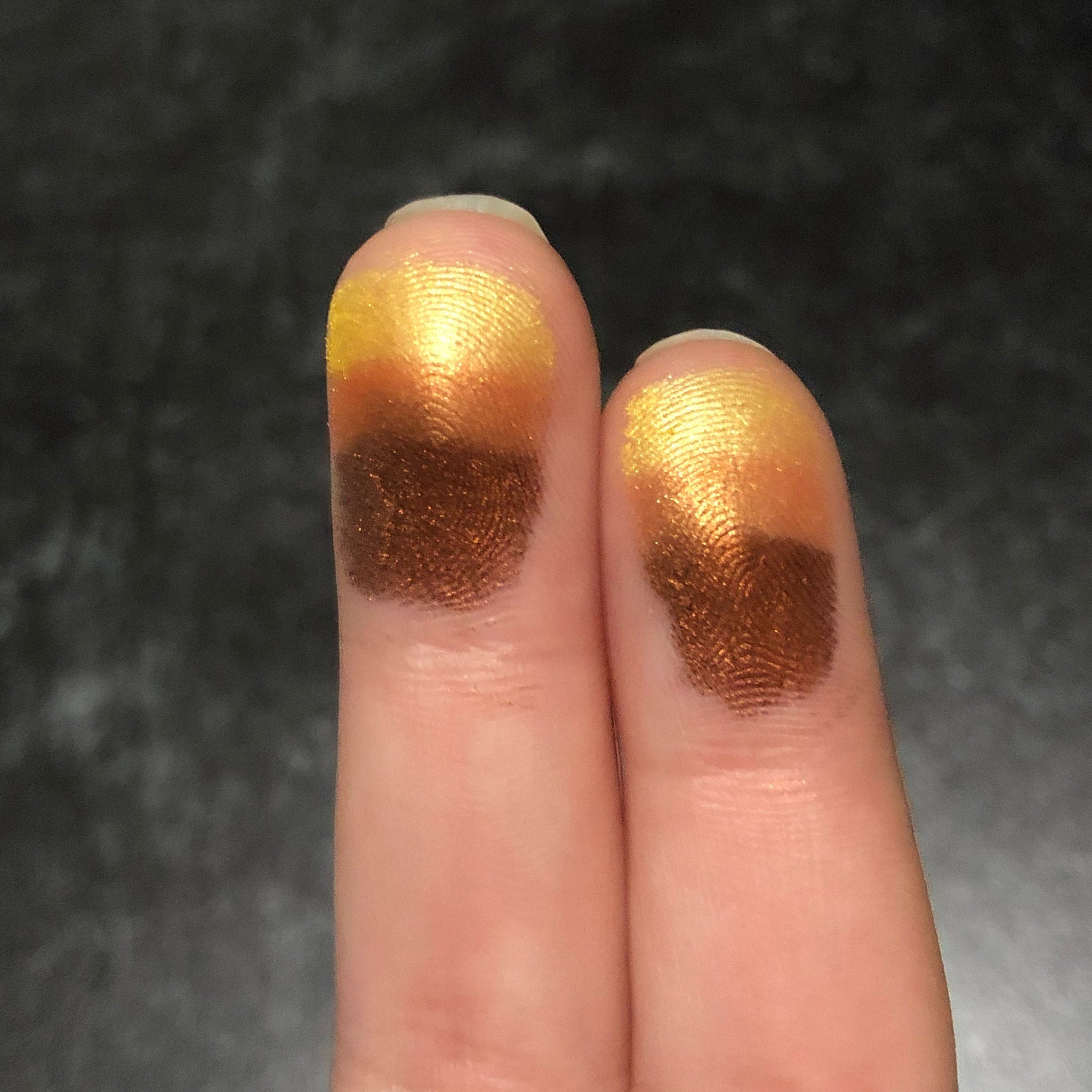 Eyeshadow swatches, gold and brown metallic colors on fingertips, finger impressions visible
