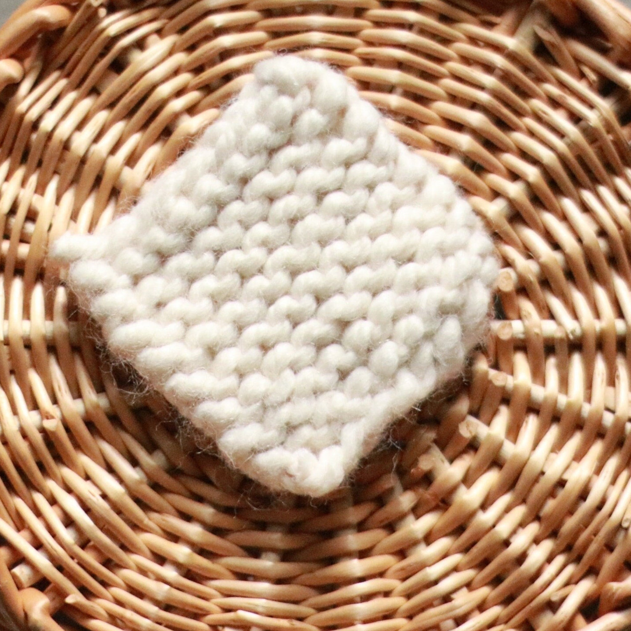 Makeup remover scrubbie pad, off-white knitted square, set in a woven basket