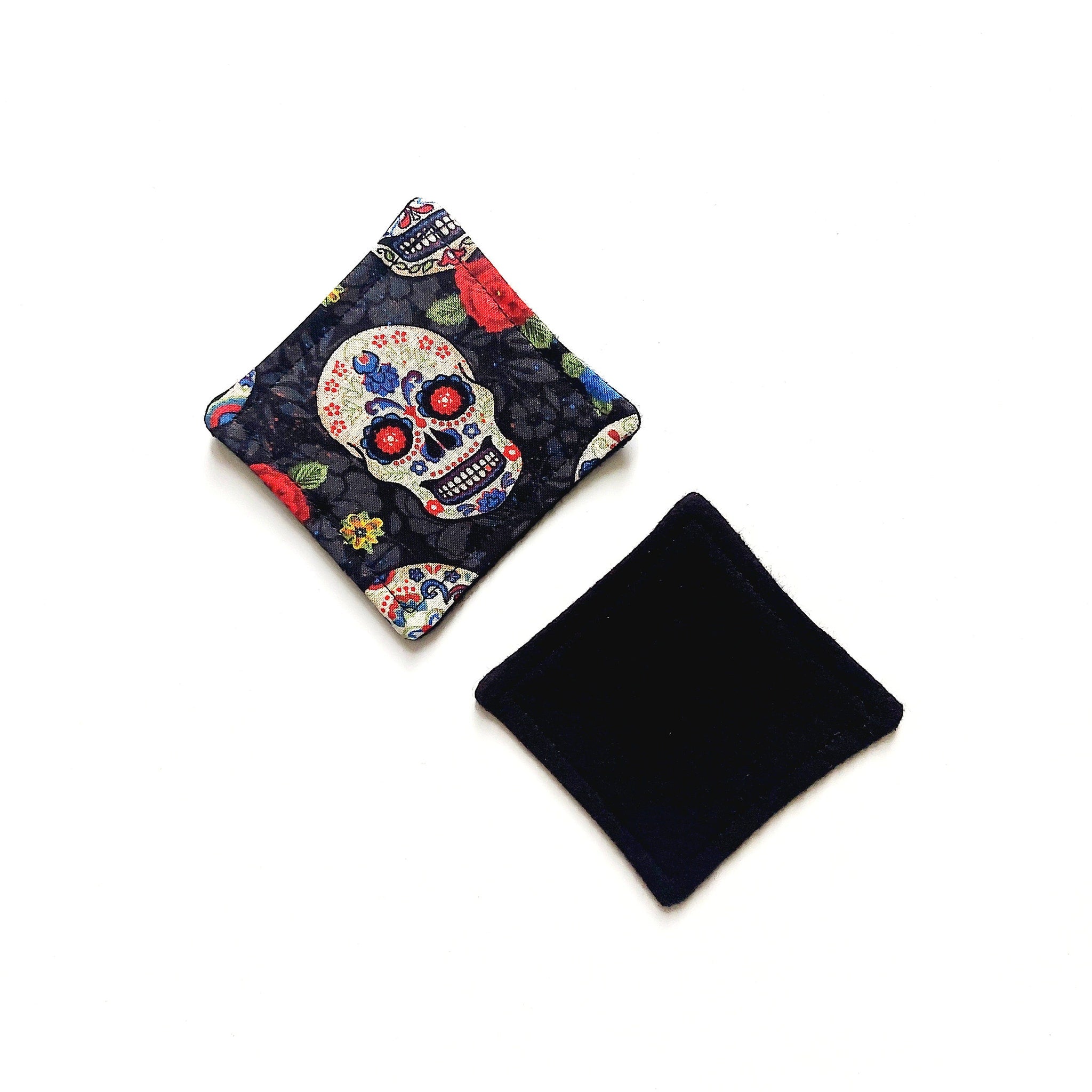 Coasters with skull pattern, black fabric, and square shape on white surface